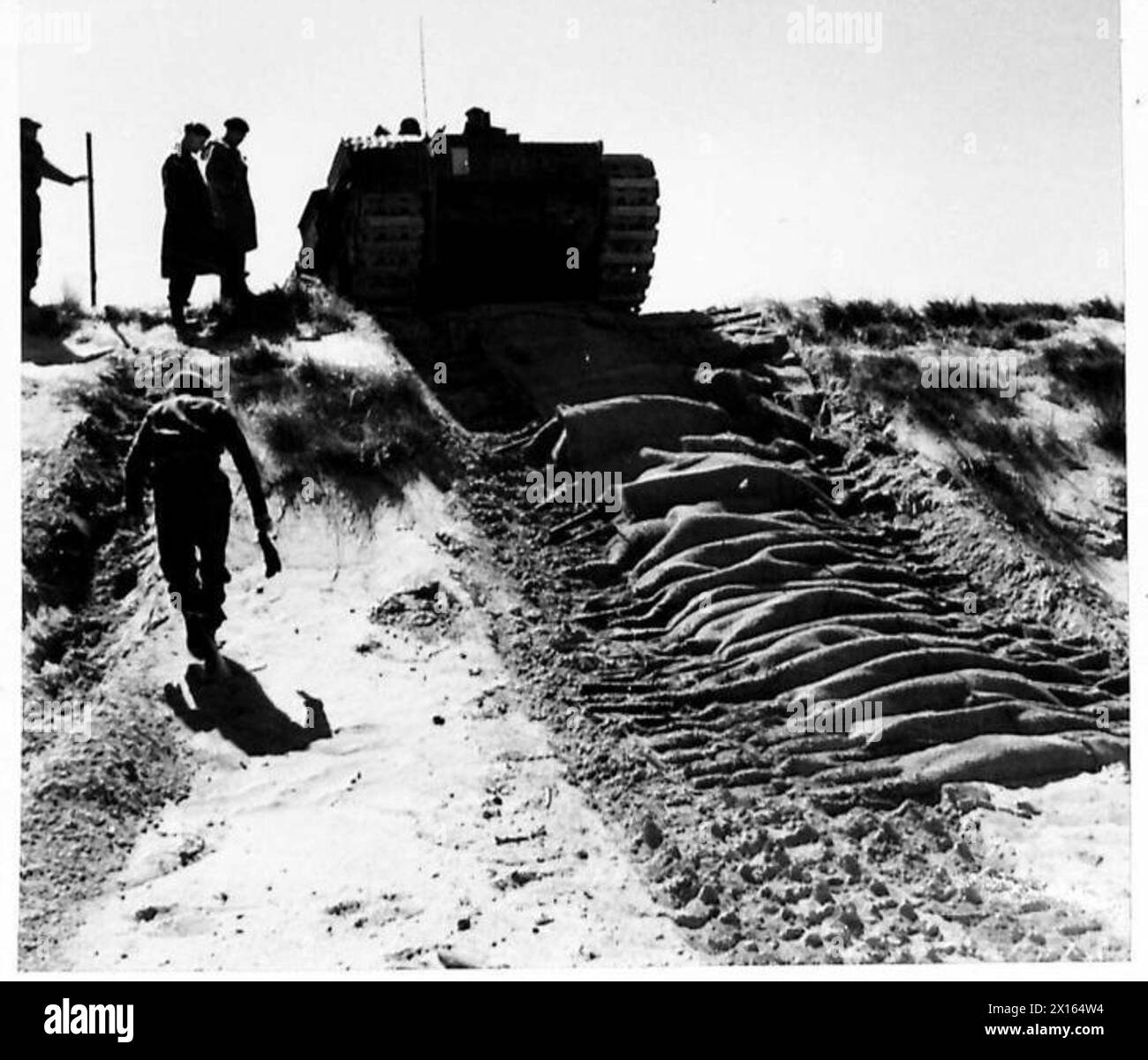 Il carro armato Churchill dell'esercito britannico si arrampica su una duna di sabbia su un tappeto posato da un veicolo A.V.R.E durante le operazioni della 79th Armoured Division. Foto Stock