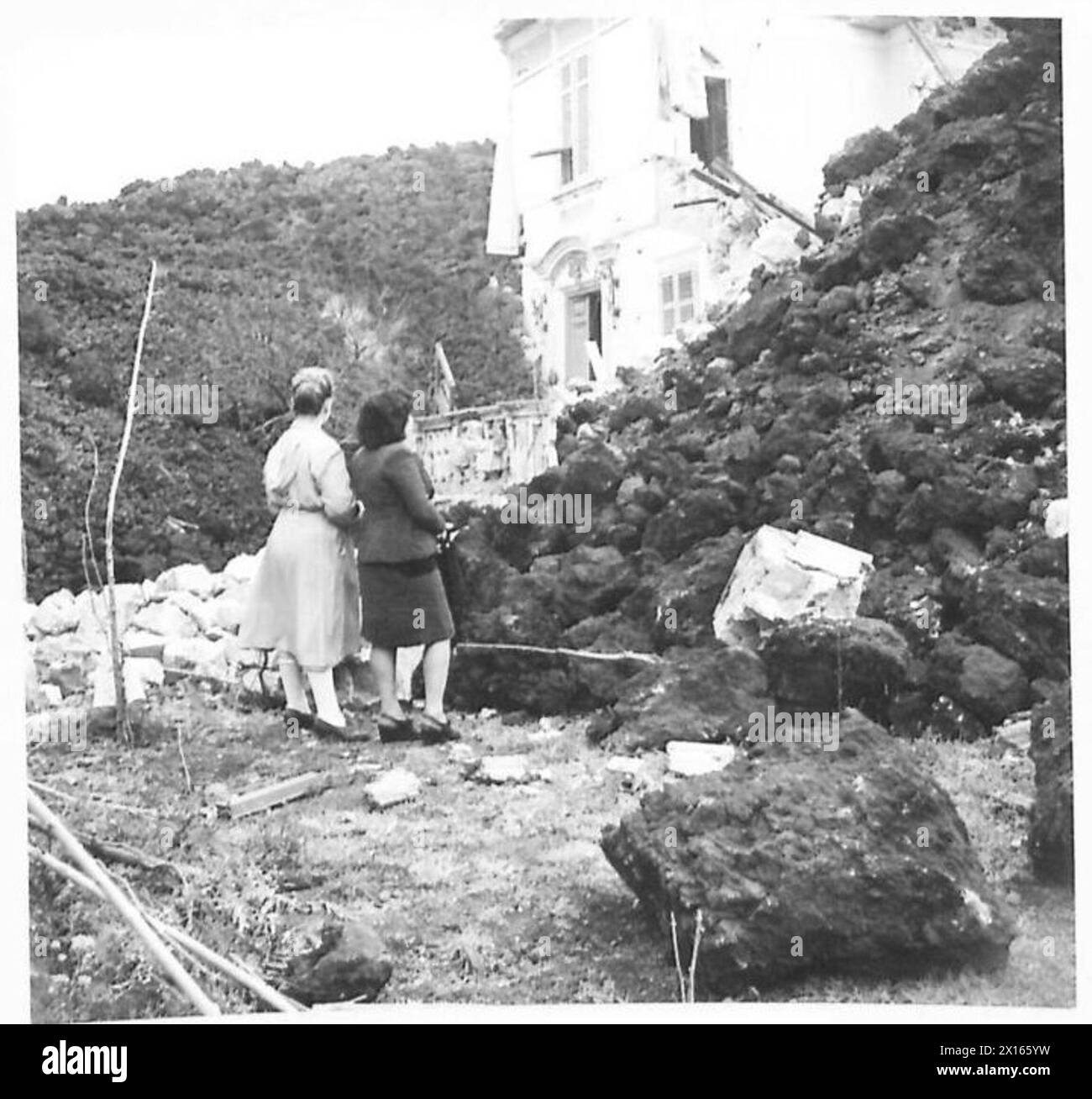 Due ragazze italiane osservano un edificio scolastico che viene sommerso da un fiume vulcanico proveniente dal Vesuvio, documentato dall'esercito britannico nella zona della Quinta Armata d'Italia. Foto Stock