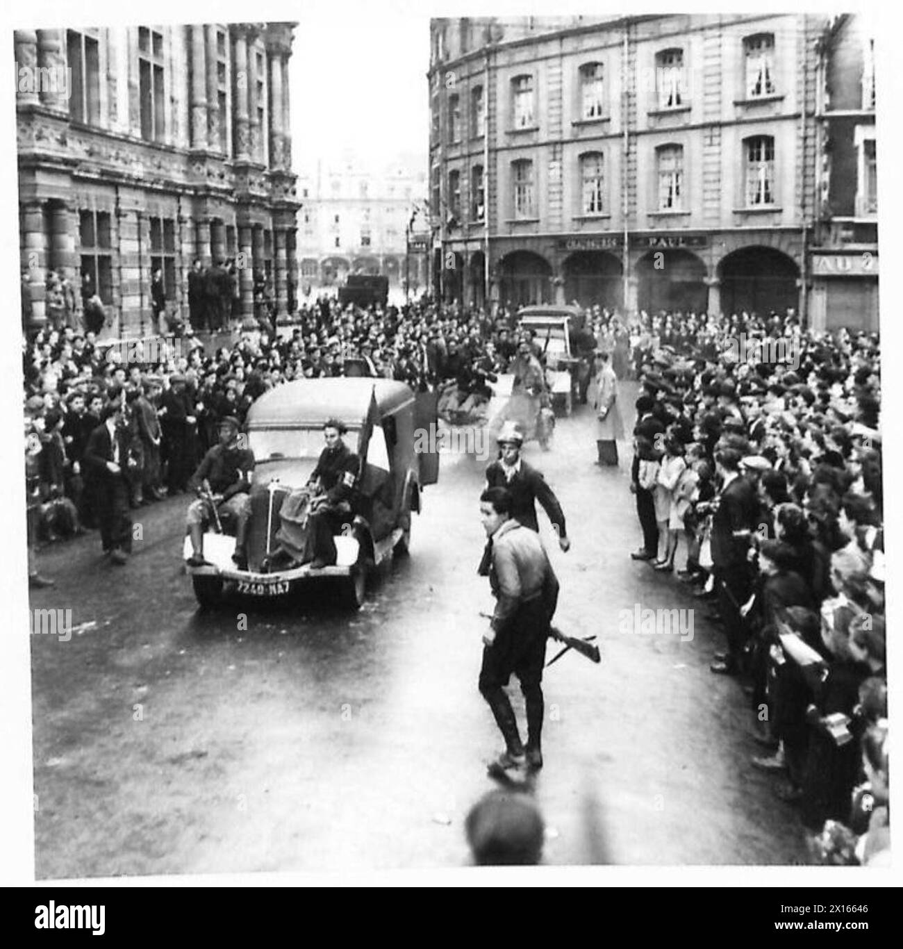 I membri delle forze francesi dell'interno (FFI) sfilano per le strade di Arras in veicoli tedeschi catturati, applauditi dai civili locali. I prigionieri tedeschi sono scortati lungo le strade addossate a bordo di camion tedeschi. Una folla si raduna mentre un giovane affronta un ritratto di Hitler. Foto Stock