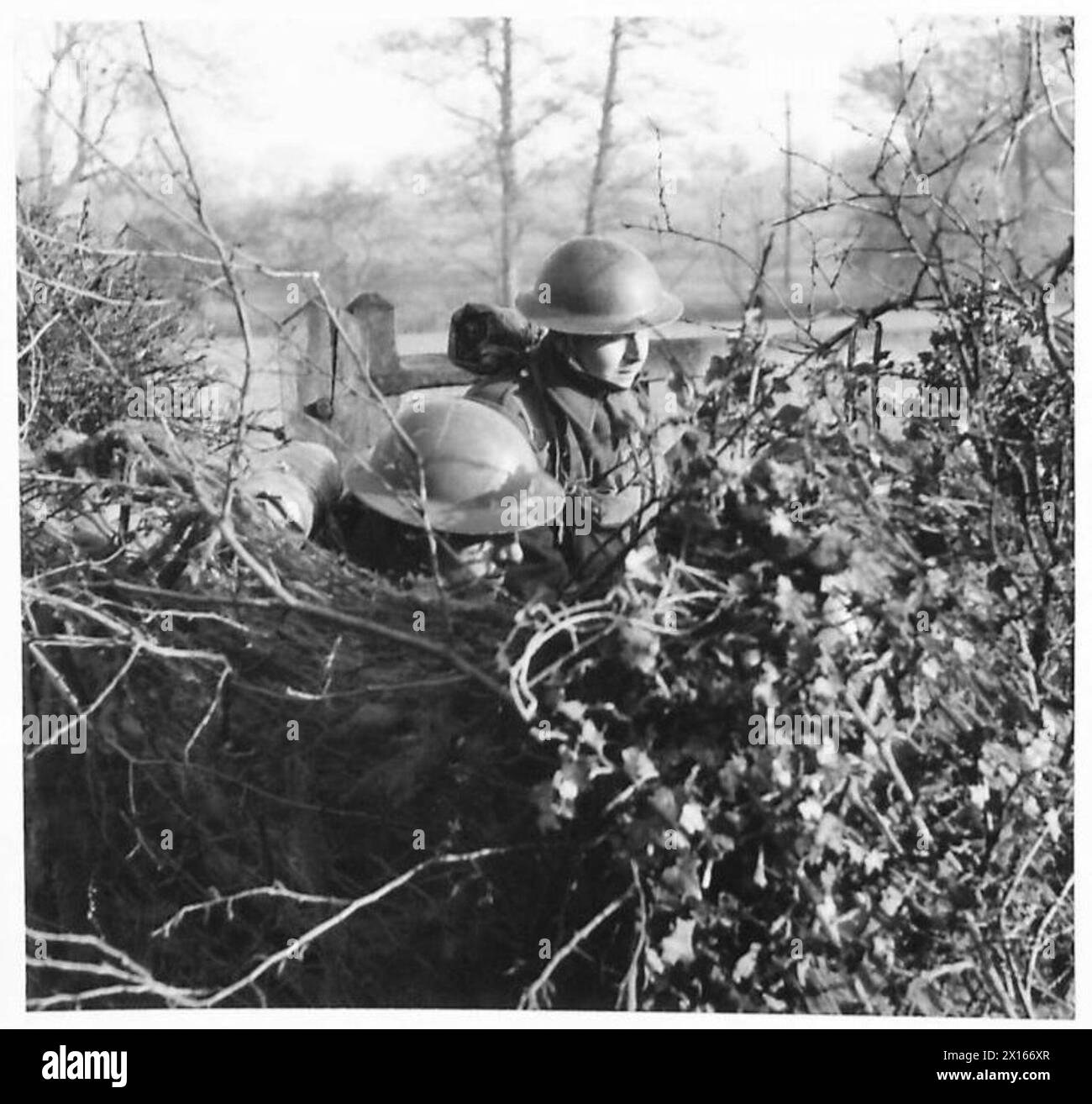 Membri della 70th Anti-Tank Battery con una pistola mimetica esposta sul ciglio della strada. Foto Stock