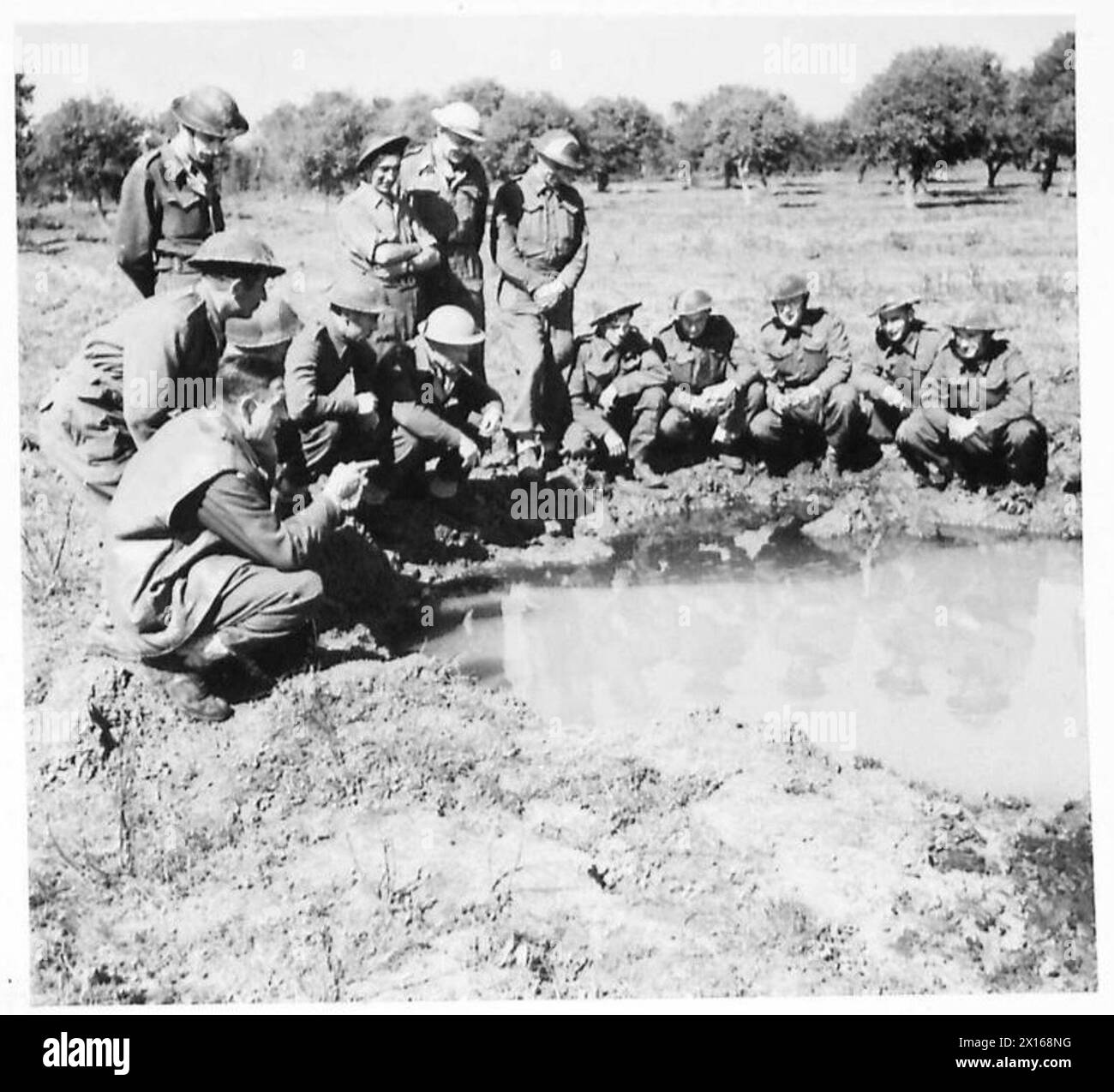 Il maggiore Carter dimostra il pericolo rappresentato dall'acqua accumulata nei buchi della testa di ponte di Anzio come parte della prevenzione della malaria. Foto Stock