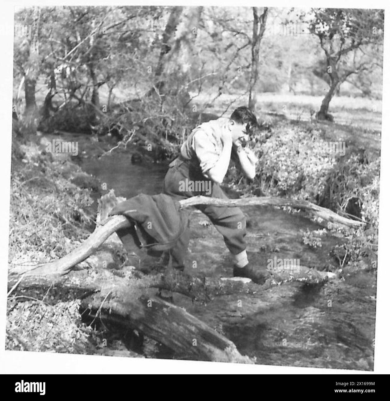 Un uomo si lava in un ruscello mentre vive in campagna, dimostrando l'igiene quotidiana e le attività all'aperto. Foto Stock