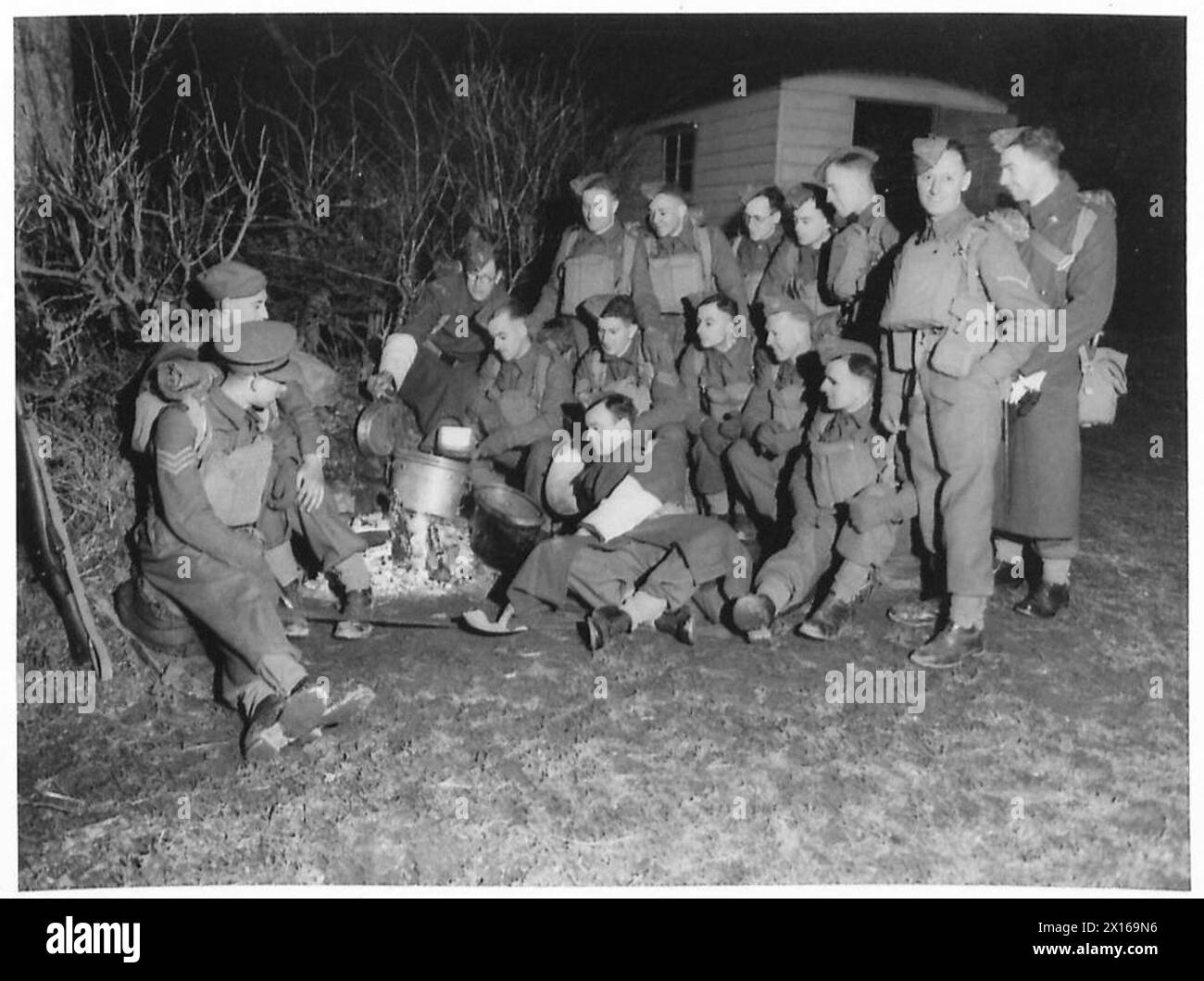 Durante un'esercitazione notturna, le truppe di una divisione dell'esercito britannico aspettano che le loro razioni vengano riscaldate come parte dell'addestramento operativo e sul campo. Foto Stock