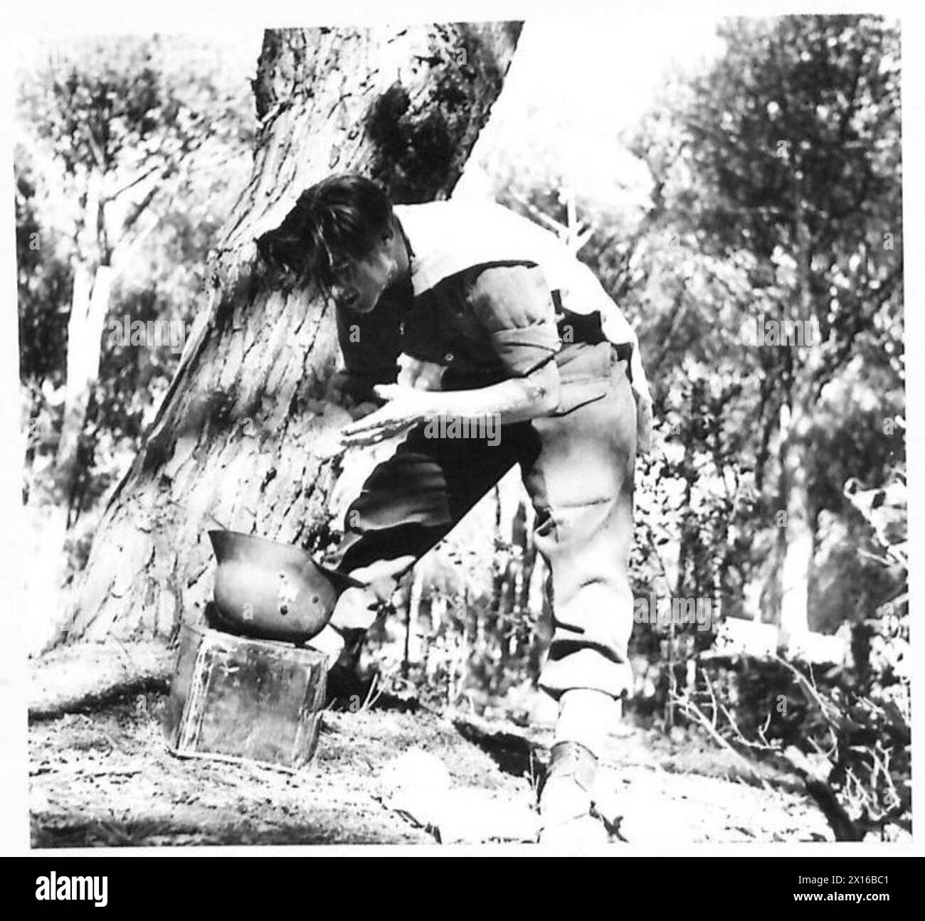 Private Johnson, parte della Quinta Armata alla testa di ponte di Anzio, si lava indossando un casco tedesco non più utilizzato dal suo proprietario originale. Foto Stock