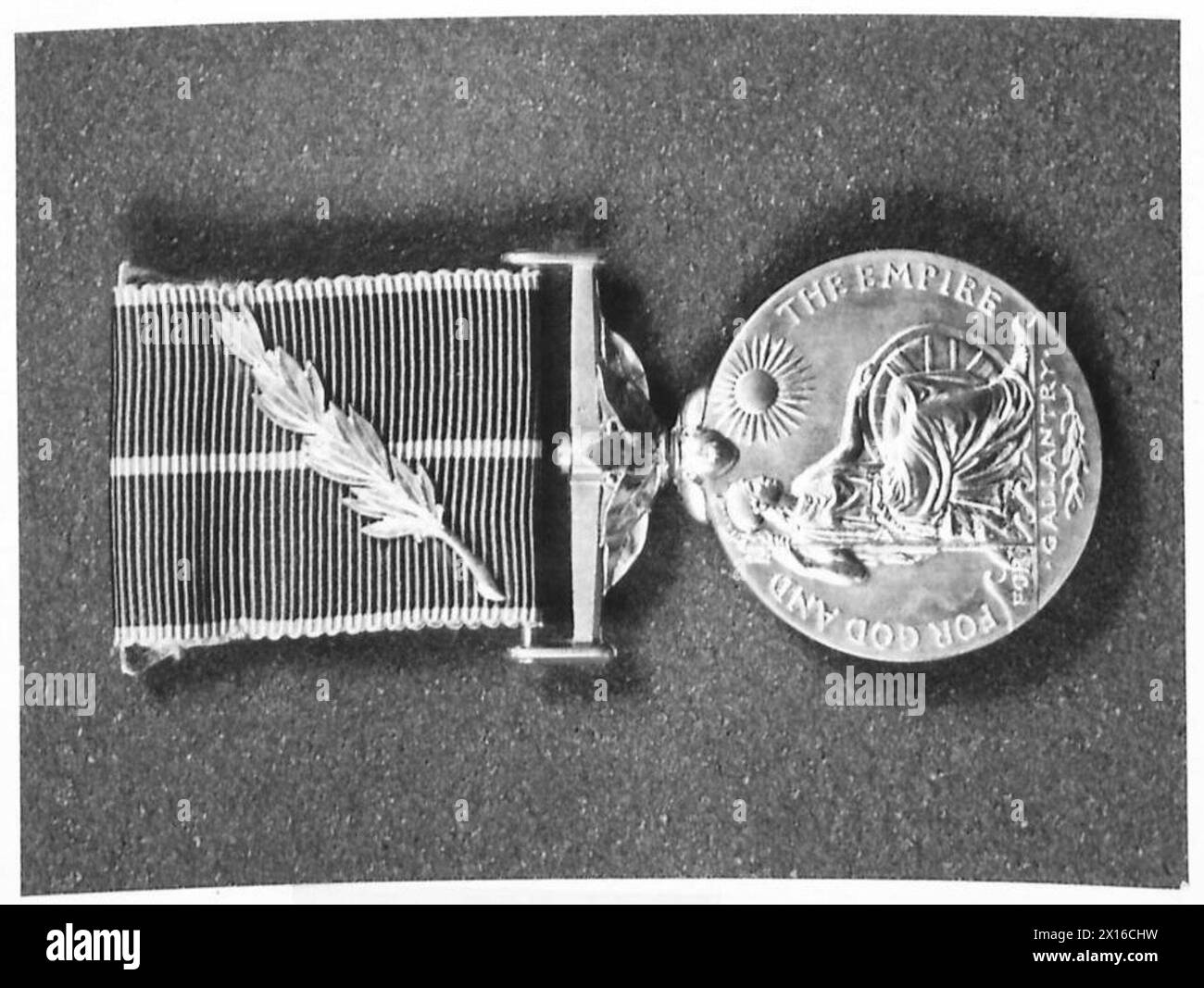 La Empire Medal presenta foglie di alloro per galanteria e foglie di quercia per un servizio meritorio, con un nastro rosa bordato di grigio, utilizzato dall'esercito britannico per i premi. Foto Stock