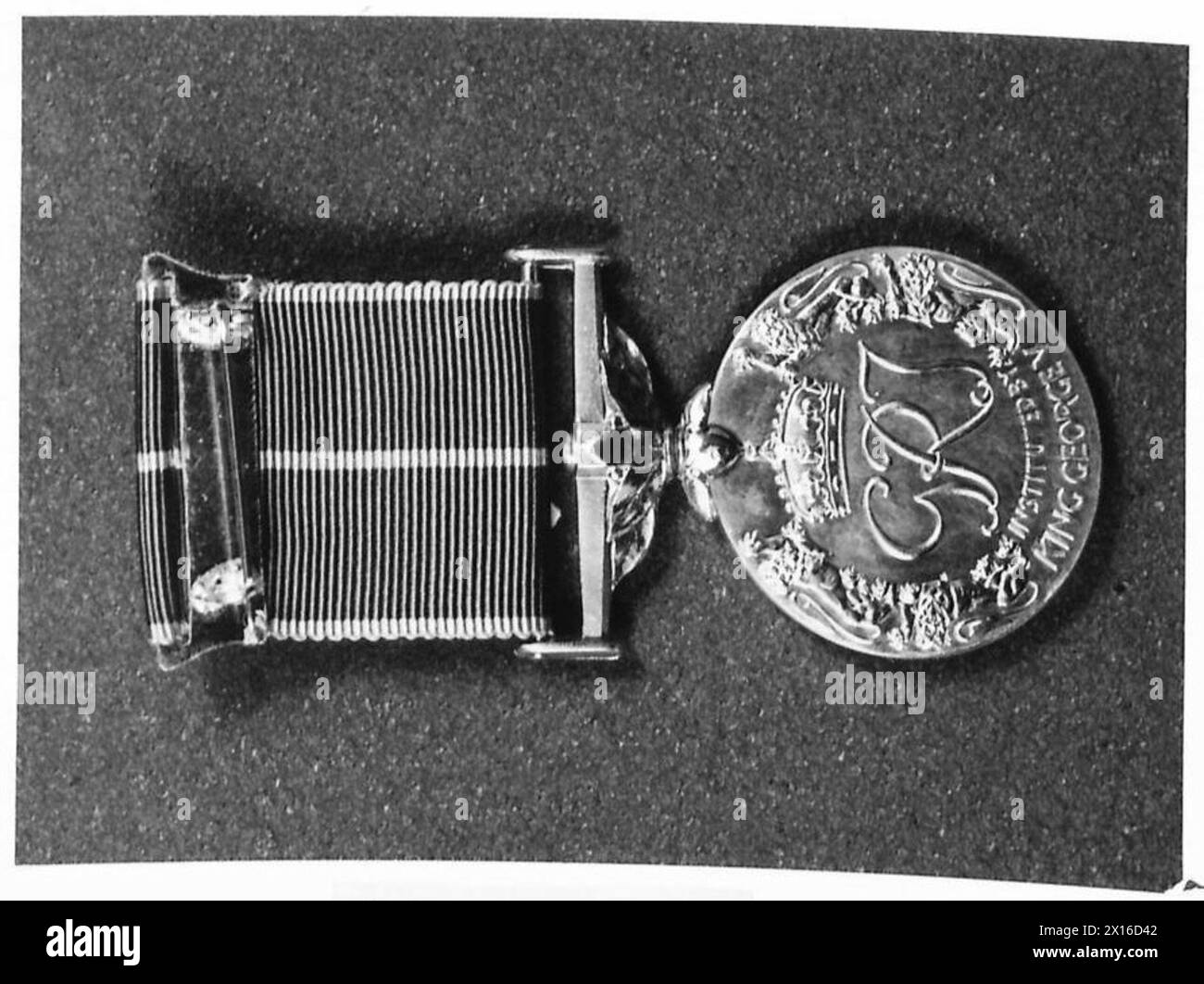 La Empire Medal presenta foglie di alloro per galanteria, foglie di quercia per un servizio meritorio, con una fascia rosa bordata di grigio perla e un centro grigio. Foto Stock