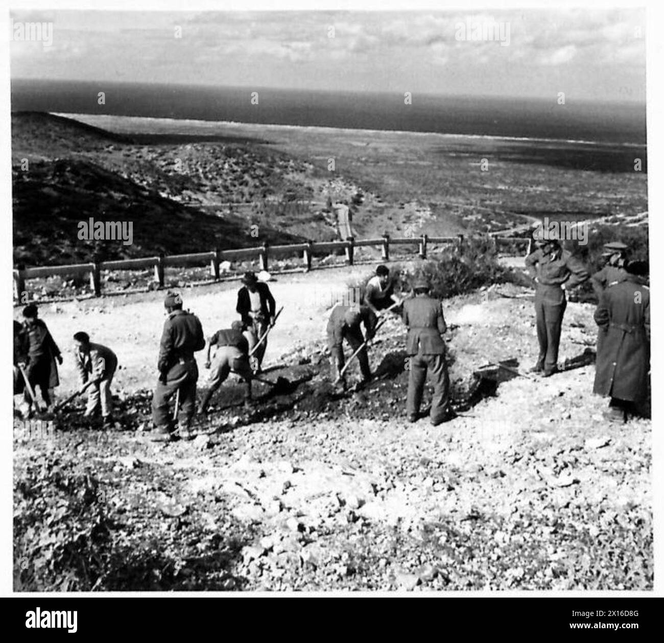 Gli abitanti locali, per lo più coloni italiani, assistettero i britannici Sappers dei Royal Engineers nella costruzione di una strada di deviazione intorno a un tratto distrutto 16 miglia ad ovest di Barce, lavorando sul nuovo by-pass che collega la strada principale. Foto Stock