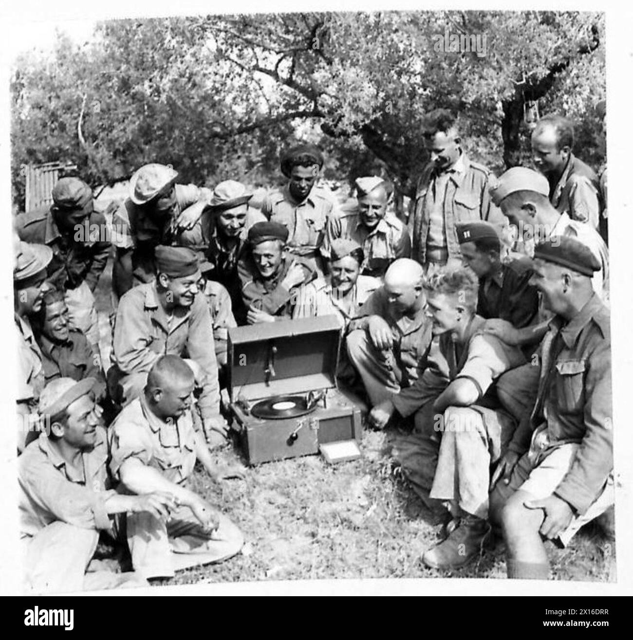 Gli ingegneri americani che prestano servizio nell'Ottava Armata interagiscono con le truppe neozelandesi, inglesi e scozzesi attorno a un lettore musicale portatile da campo noto come "Music Box". Foto Stock