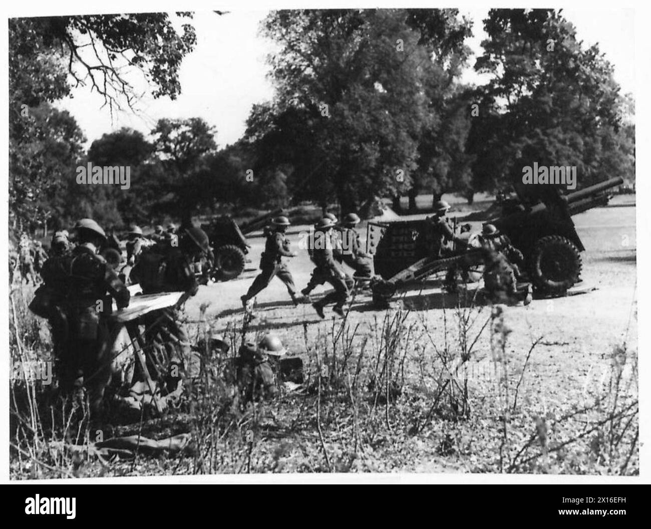 Gli equipaggi del 79th East Anglian Field Regiment corrono verso i loro cannoni per prendere posizione all'inizio di un'esercitazione a Kennett, nell'East Anglia. Foto Stock