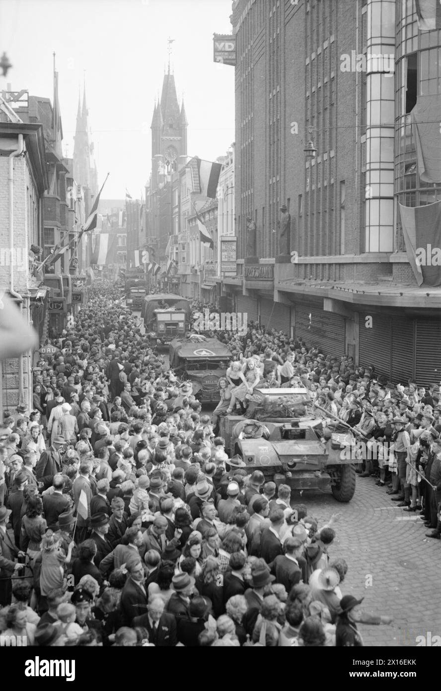 Le auto corazzate Daimler e i camion dell'esercito britannico passano attraverso folle civili a Eindhoven durante la liberazione dell'Europa nord-occidentale, il 20 settembre 1944. Foto Stock