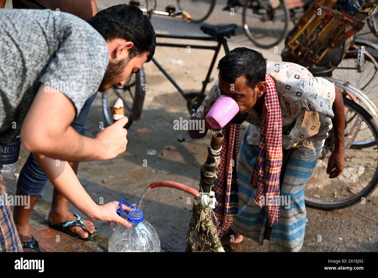 Dacca, Bangladesh. 15 aprile 2024. Un autista di risciò sta bevendo l'acqua da un gasdotto lungo la strada durante la giornata ad alta temperatura a Dacca, Bangladesh, il 15 aprile 2024 credito: Mamunur Rashid/Alamy Live News Foto Stock