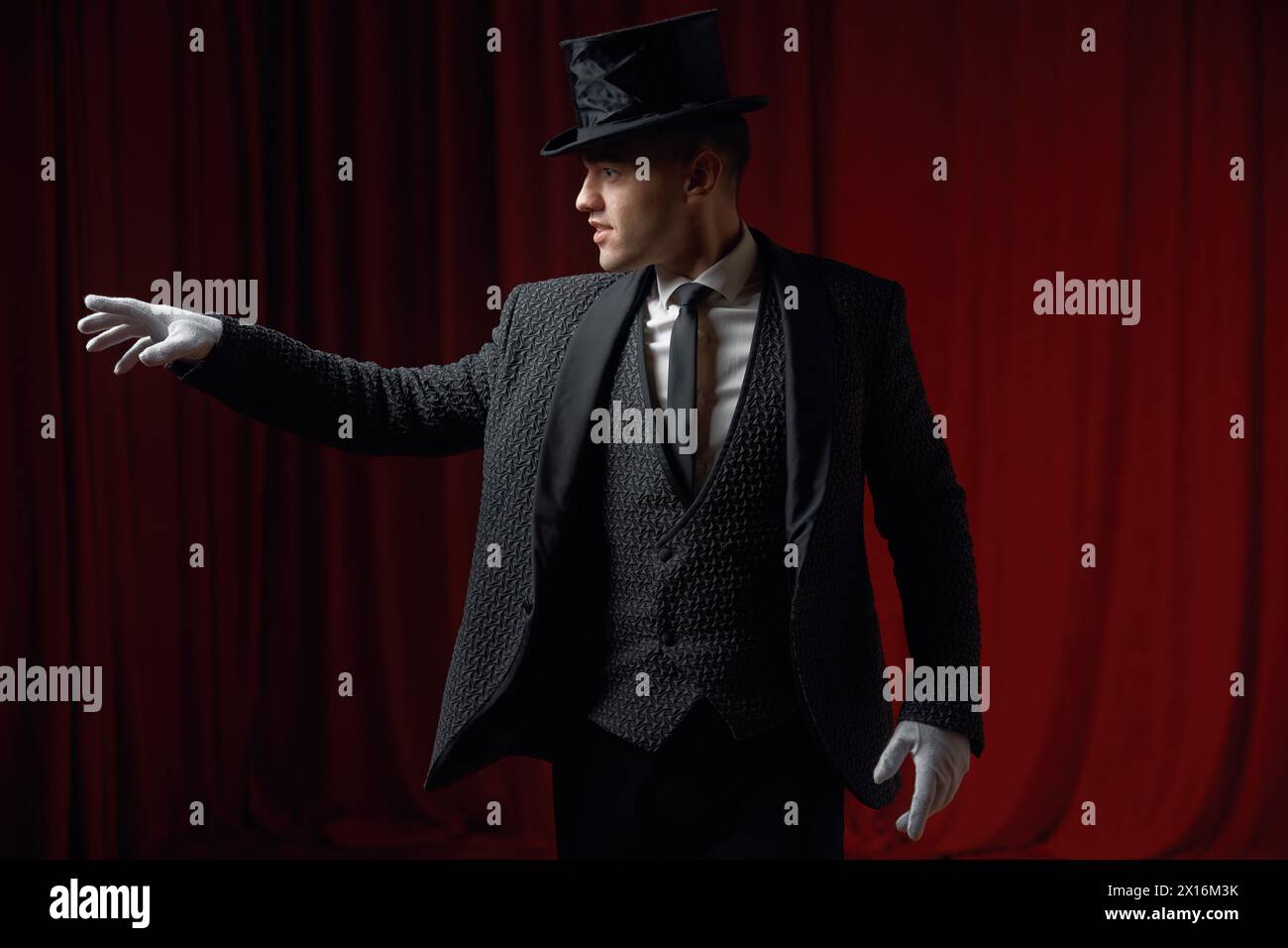 Showman alla moda o illusionista in un cappotto e cappello sul palco Foto Stock