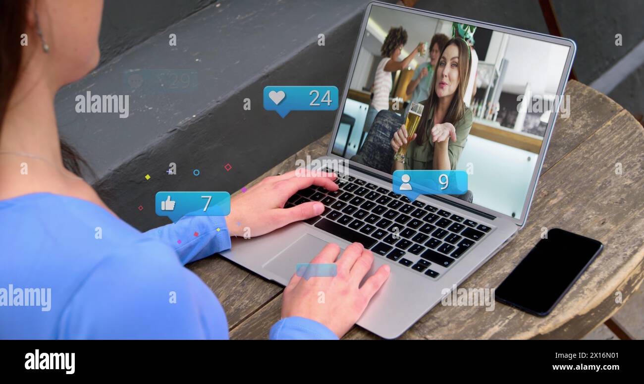 Immagine di icone dei media su una donna caucasica che riceve un'immagine del laptop con amici diversi Foto Stock