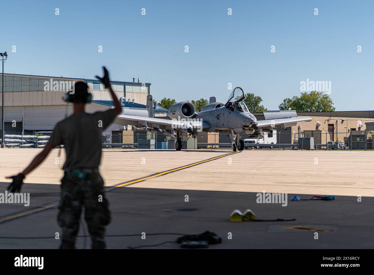 Un uomo è in piedi sulla pista, salutando un jet da caccia. La scena è tesa ed eccitante, mentre il jet da combattimento si sta preparando per il decollo Foto Stock