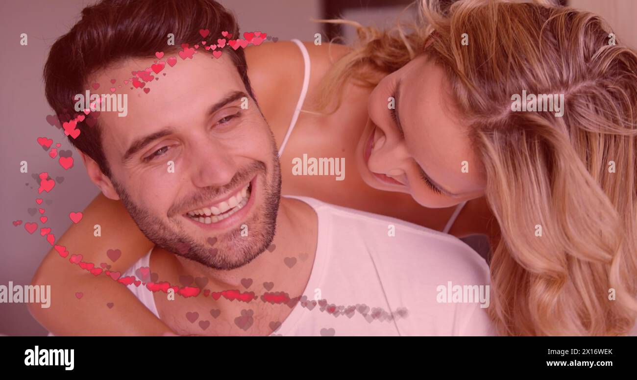Immagine di cuori rossi su una coppia innamorata che abbraccia e sorride Foto Stock