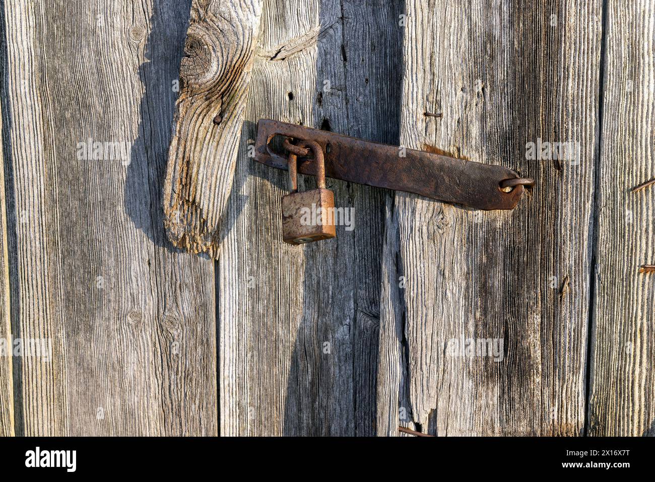 vecchie porte in legno chiuse con lucchetto, parte dell'edificio abbandonato ma con porte chiuse su un lucchetto metallico Foto Stock