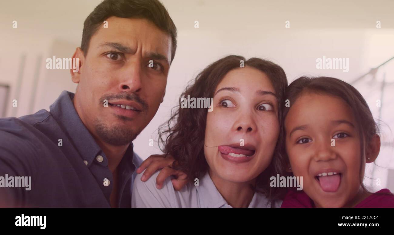 Immagine di bokeh su una famiglia birazziale felice che fa facce divertenti Foto Stock