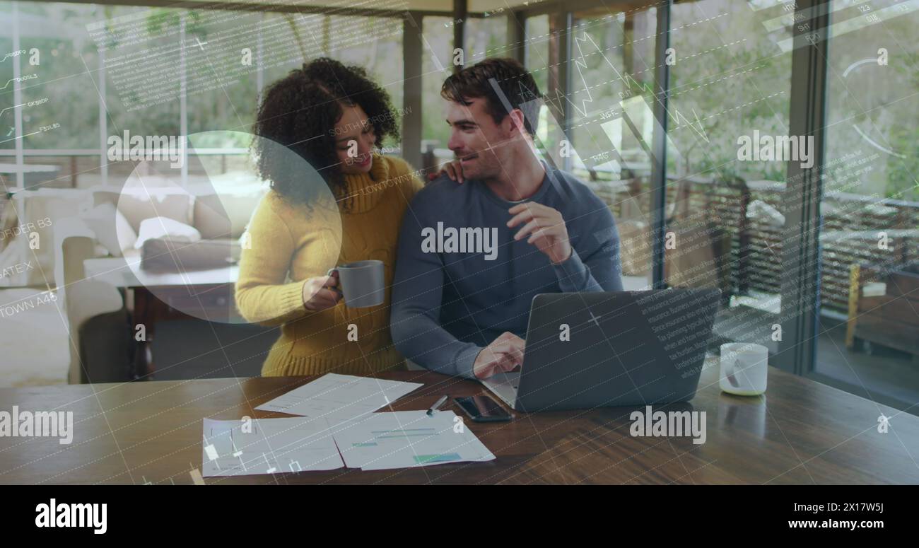 Immagine di grafici ed elaborazione dei dati su una coppia birazziale felice che utilizza un notebook a casa Foto Stock