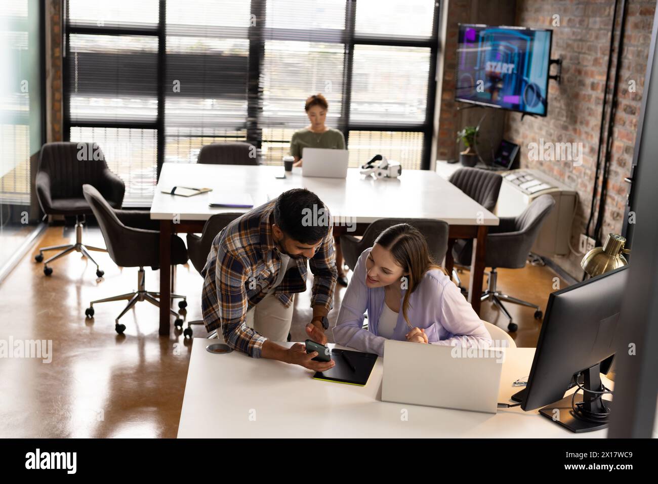 Colleghi asiatici maschi e caucasici che esaminano i contenuti su un tablet in un moderno ufficio aziendale Foto Stock