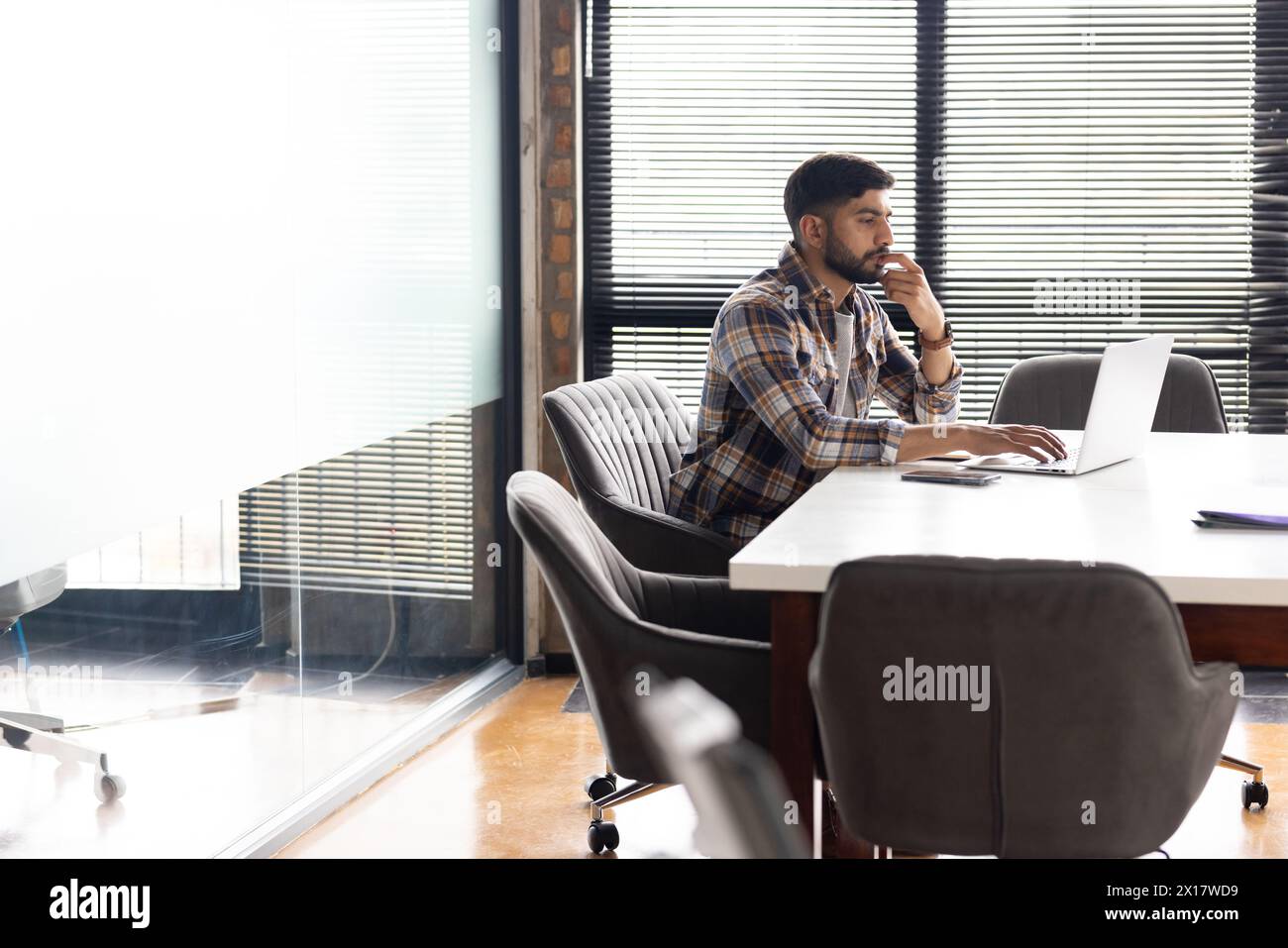 Uomo asiatico che guarda con attenzione al notebook in un moderno ufficio aziendale Foto Stock