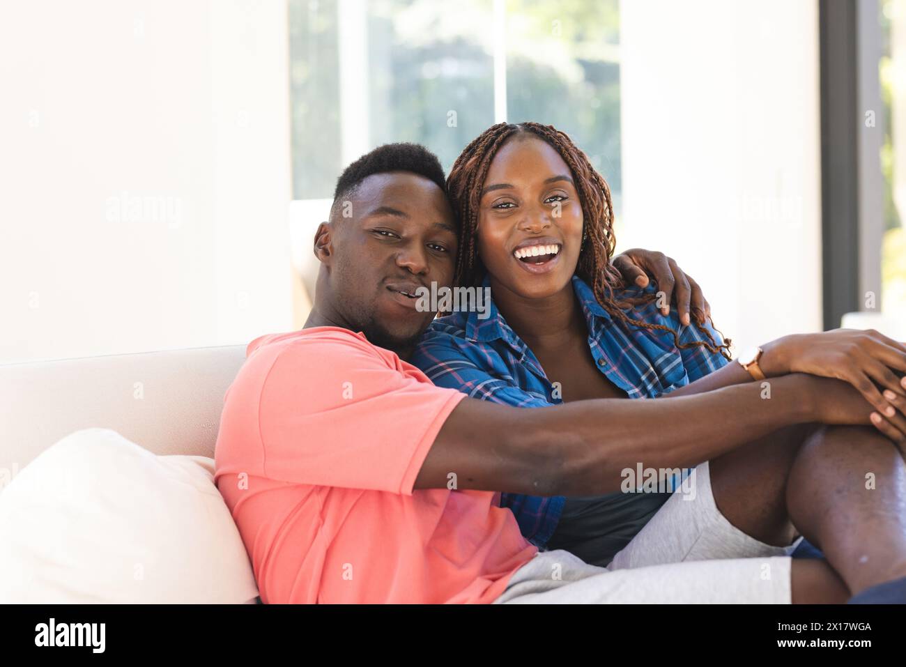Coppia afroamericana seduta vicino, sorridente alla macchina fotografica di casa Foto Stock