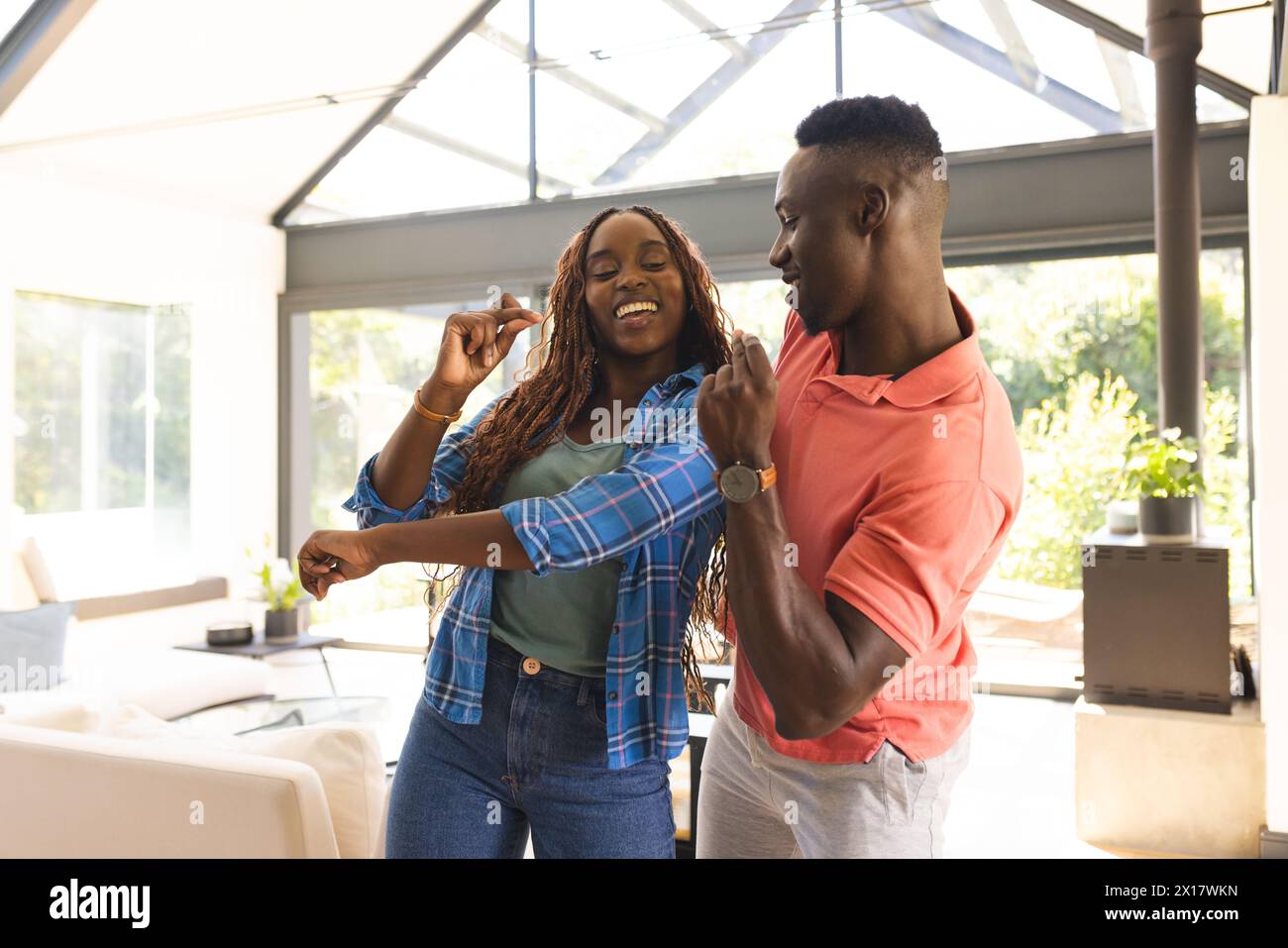 La coppia afroamericana sta ballando in una stanza soleggiata a casa Foto Stock
