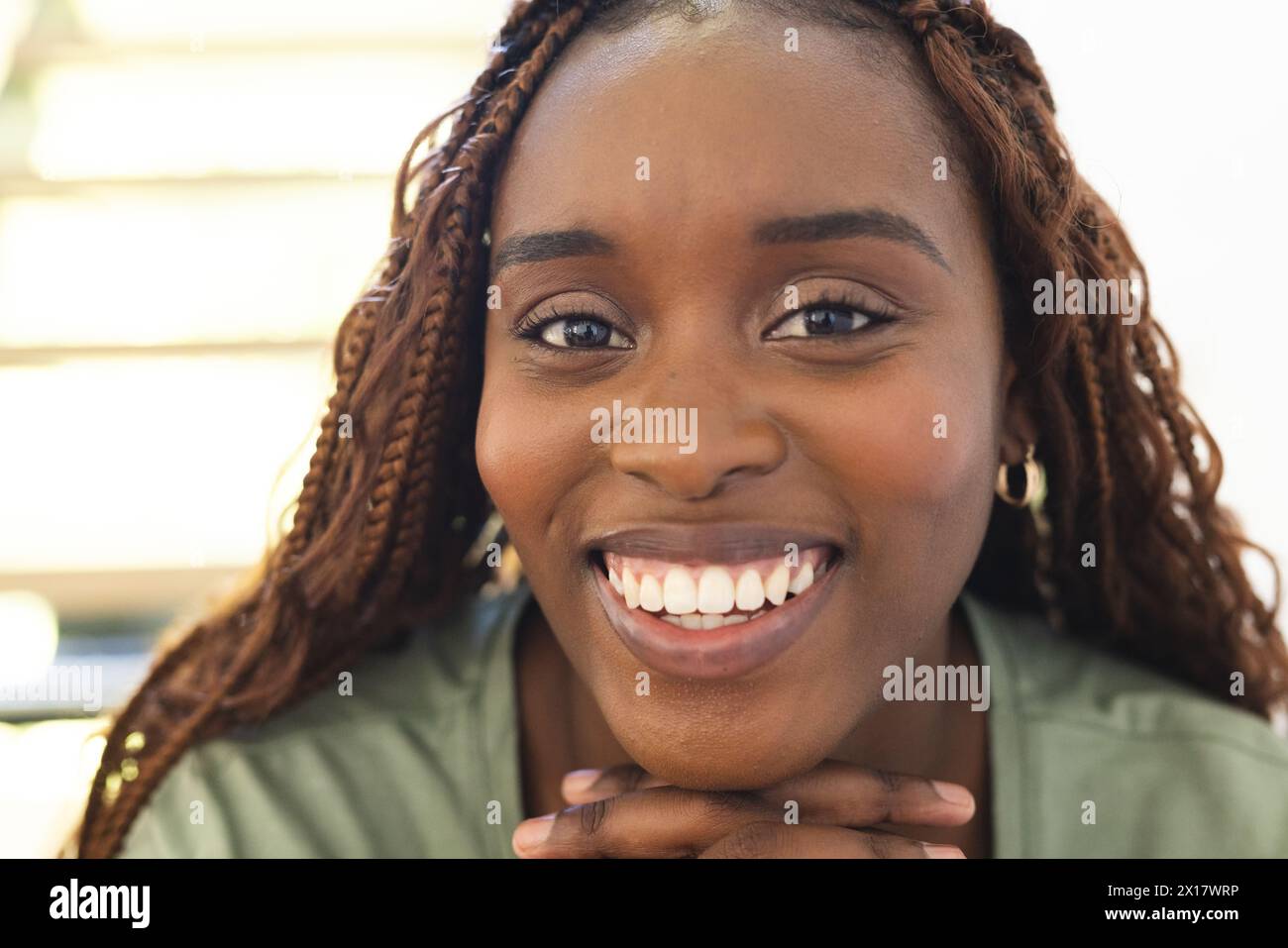 Donna afroamericana con capelli intrecciati, sorridente alla macchina fotografica di casa Foto Stock