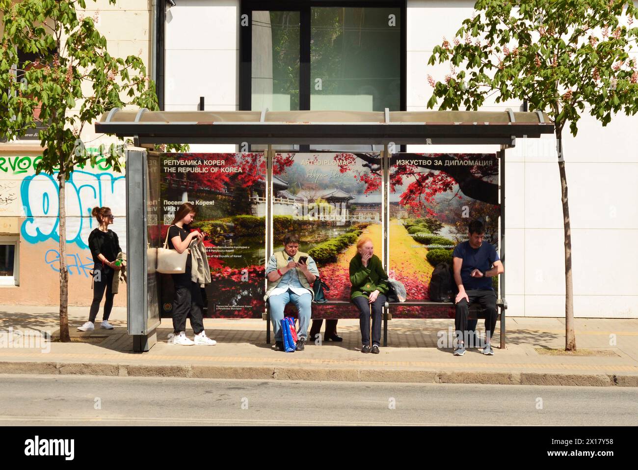 Fermata dell'autobus e persone in attesa, colorate infrastrutture urbane ad alto contrasto a Sofia Bulgaria, Europa orientale, Balcani, UE, trasporti pubblici, sciopero Foto Stock