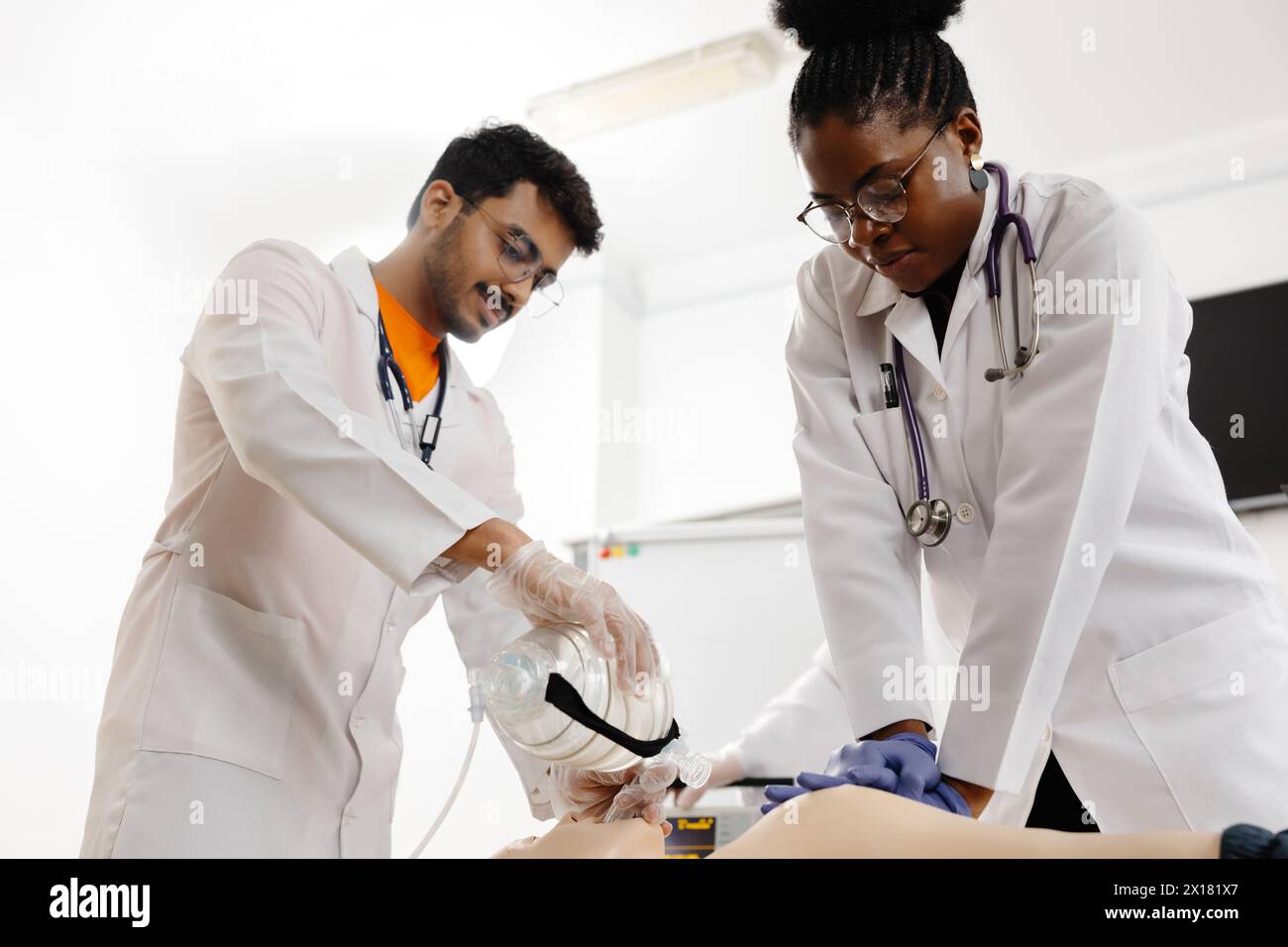 Un paio di medici professionisti stanno eseguendo con attenzione una procedura su un paziente in un ambiente ospedaliero. Foto Stock