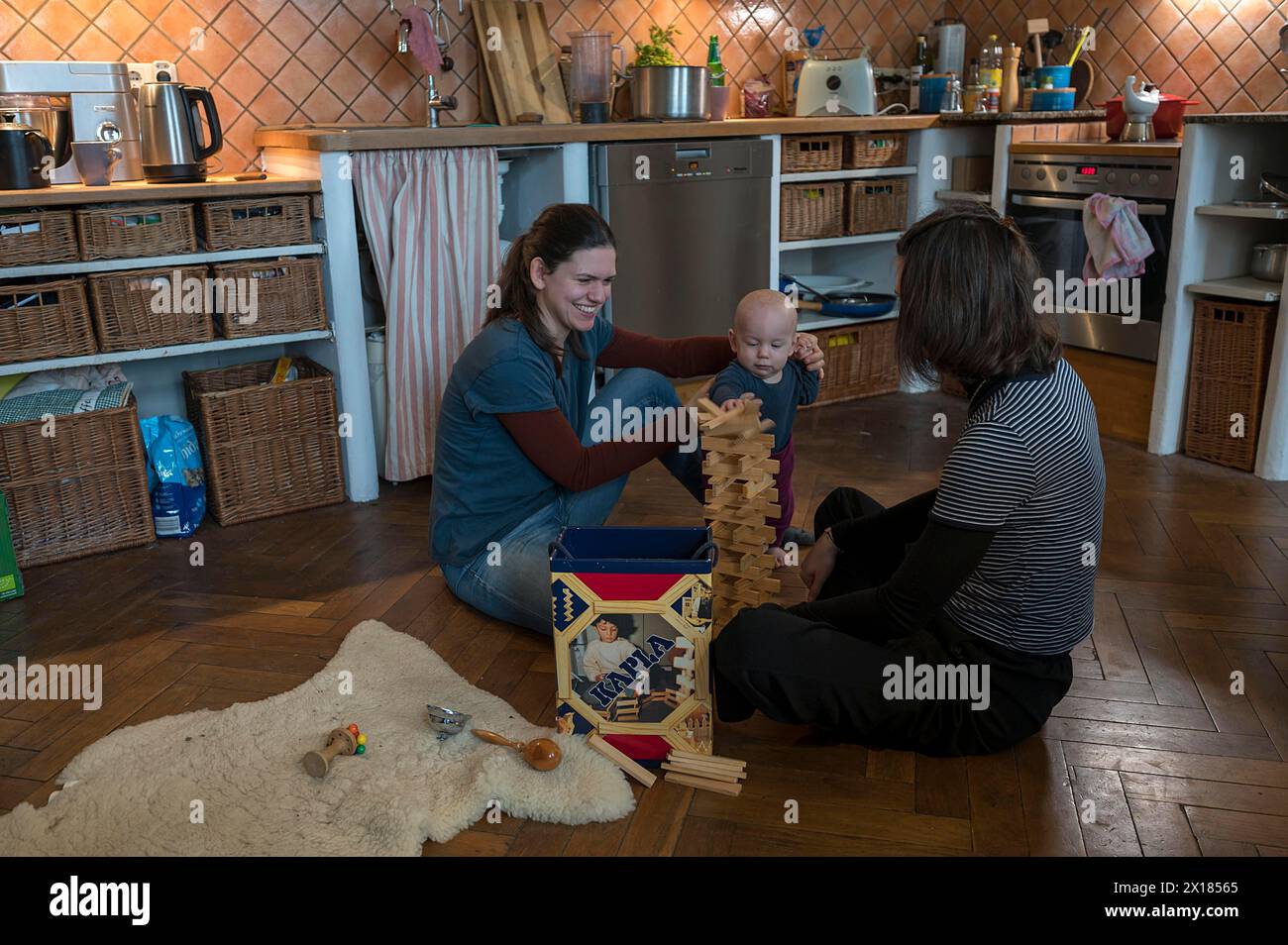 Giovane madre con sua sorella e con suo figlio, 8 mesi, che gioca sul parquet, Meclemburgo-Vorpommern, Germania Foto Stock