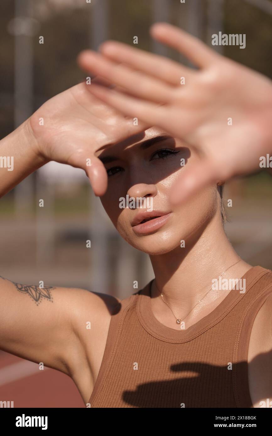 Donna giovane che protegge gli occhi dalla luce solare all'aperto Foto Stock