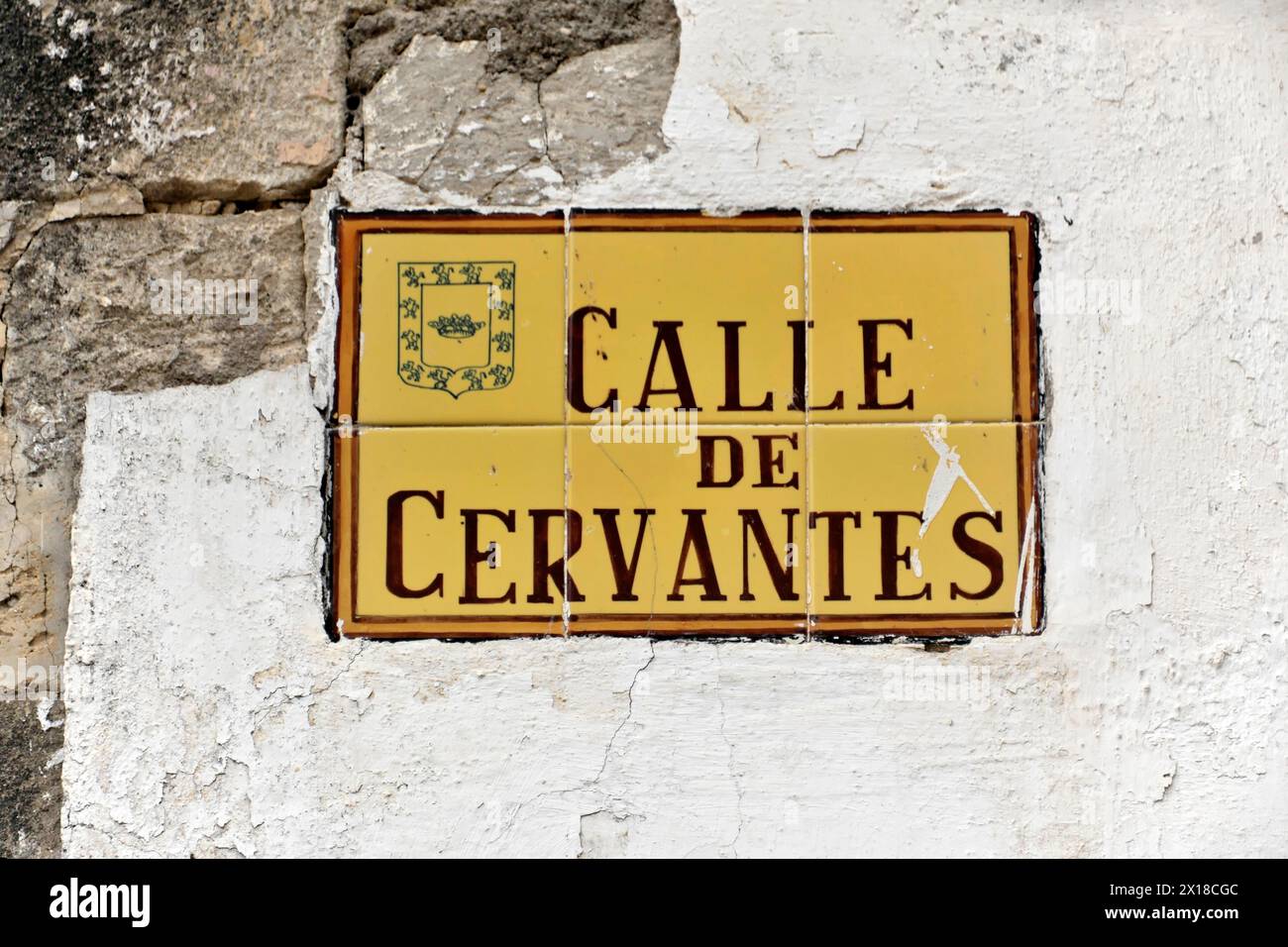 Ubeda, provincia di Jaen, cartello stradale "Calle de Cervantes" su piastrelle gialle con stemma su un muro, provincia di Jaen, Andalusia, Spagna Foto Stock