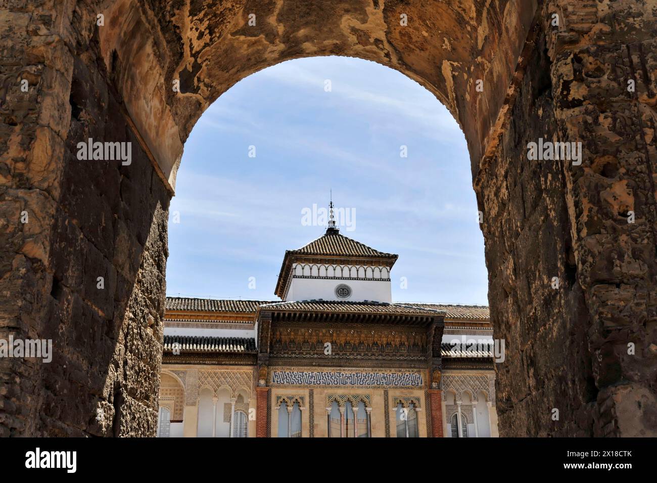 Siviglia, il Palazzo reale Real Alcazar, sito patrimonio dell'umanità dell'UNESCO, a Siviglia, ammira attraverso un arco della facciata a motivi geometrici di un edificio Foto Stock