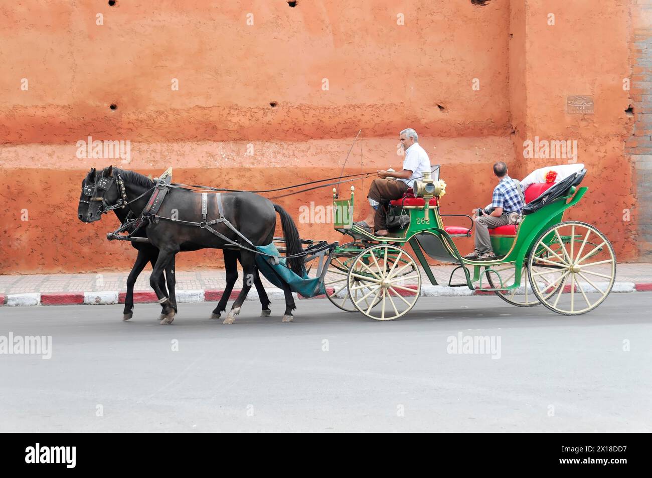 Marrakech, Una tradizionale carrozza trainata da cavalli trasporta passeggeri in una strada della città, Marrakech, Marocco Foto Stock