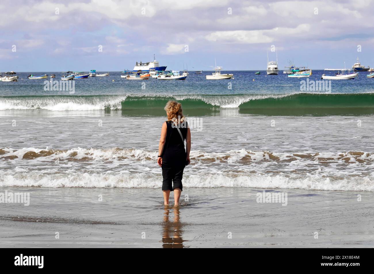 San Juan del Sur, Nicaragua, donna sulla spiaggia che guarda onde e barche, riflessioni sull'acqua, America centrale, America centrale Foto Stock