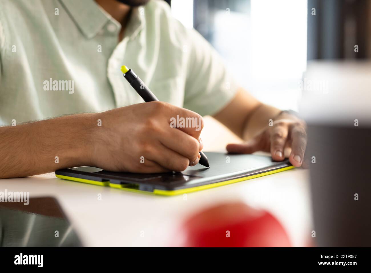Giovane uomo professionista asiatico che disegna su tablet digitale, indossa abiti casual in un business moderno Foto Stock