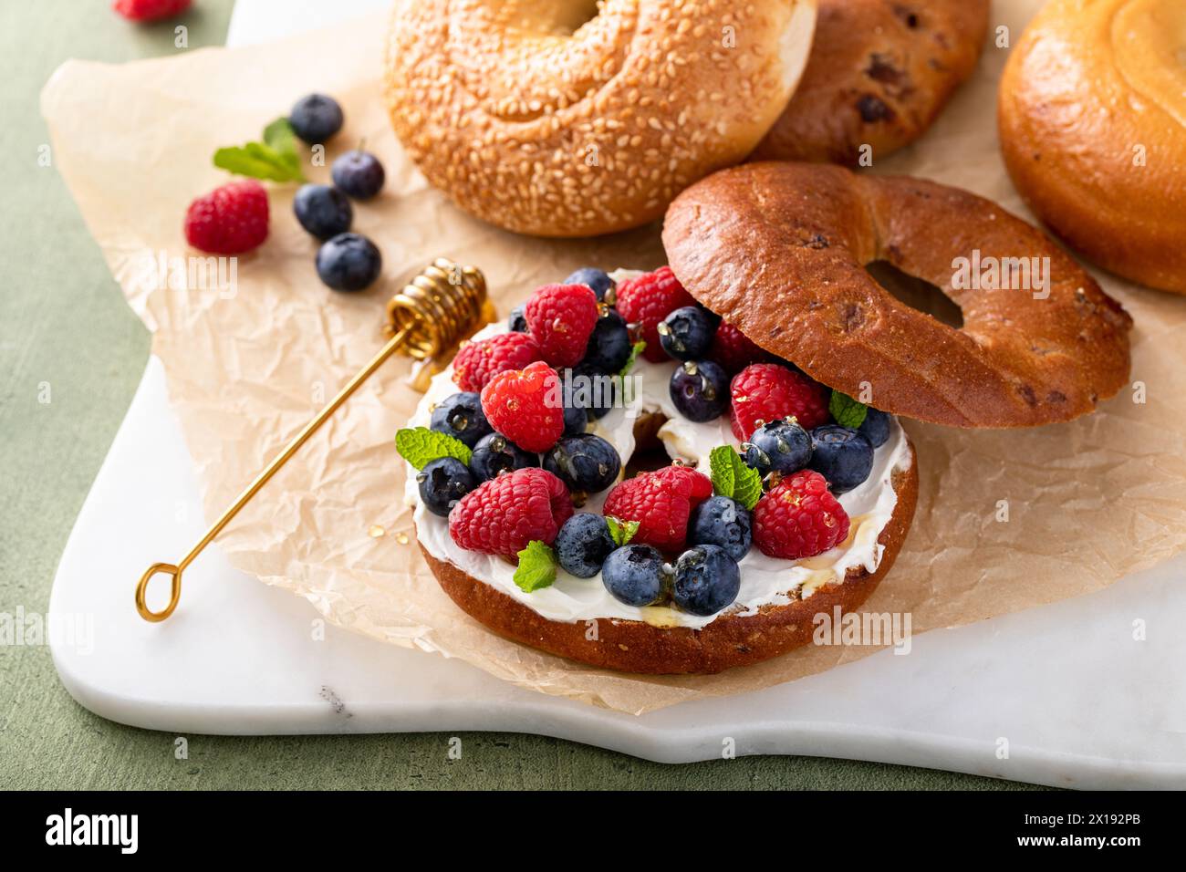 Bagel alla cannella con formaggio spalmabile, frutti di bosco freschi e miele per colazione Foto Stock