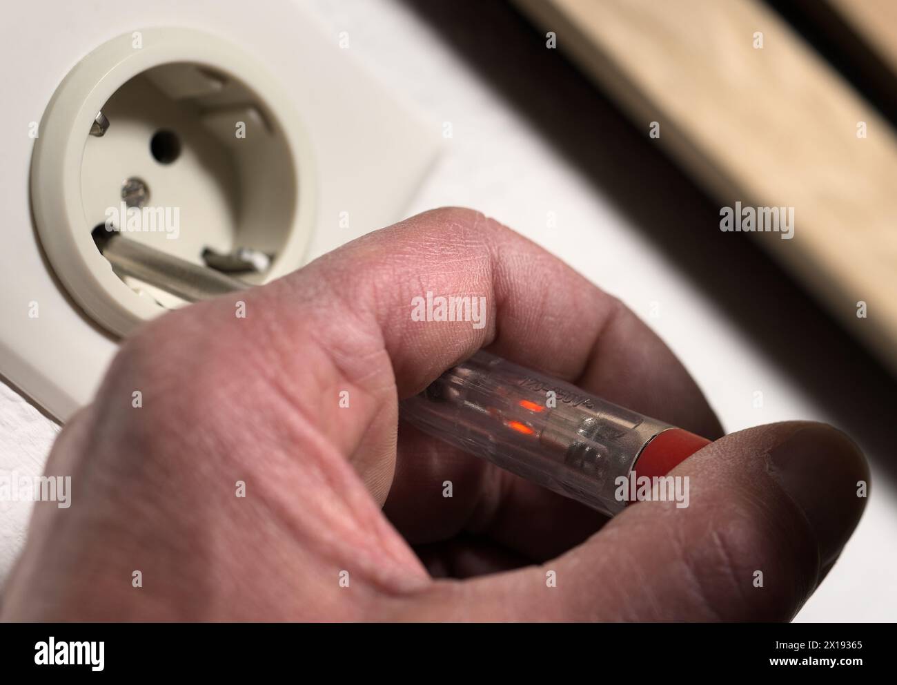Controllo della tensione della rete elettrica sulla presa di corrente a muro con il cacciavite del tester di fase del circuito elettrico Foto Stock