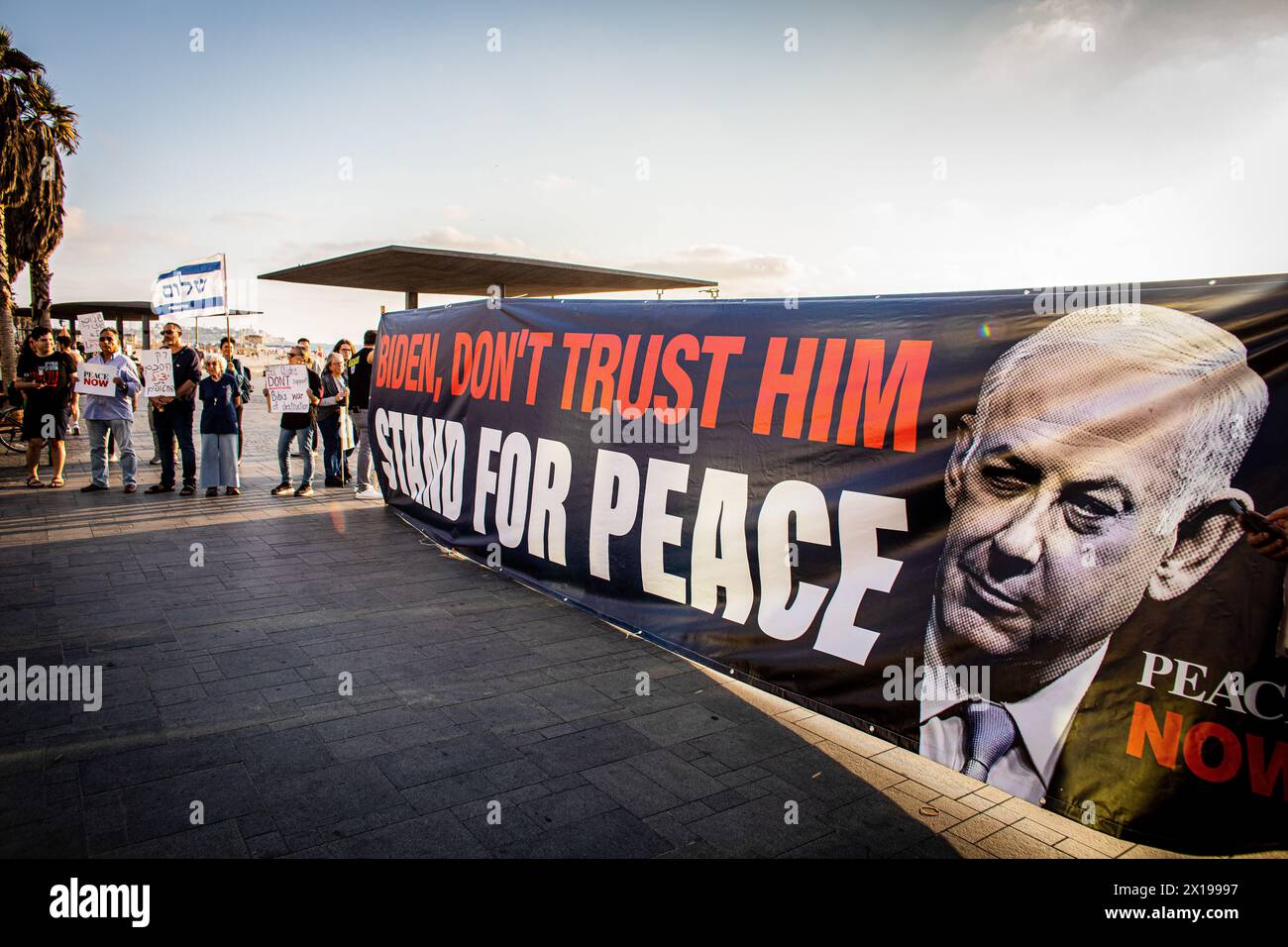 Tel Aviv, Israele. 15 aprile 2024. I manifestanti tengono uno striscione che invita il presidente degli Stati Uniti Joe Biden a non fidarsi del primo ministro israeliano Benjamin Netanyahu durante una manifestazione. Israele ha promesso di "determinare un prezzo” dall'Iran dopo un attacco senza precedenti su larga scala con drone e missili nel fine settimana che ha intensificato le tensioni regionali innescate dalla guerra a Gaza. Credito: SOPA Images Limited/Alamy Live News Foto Stock
