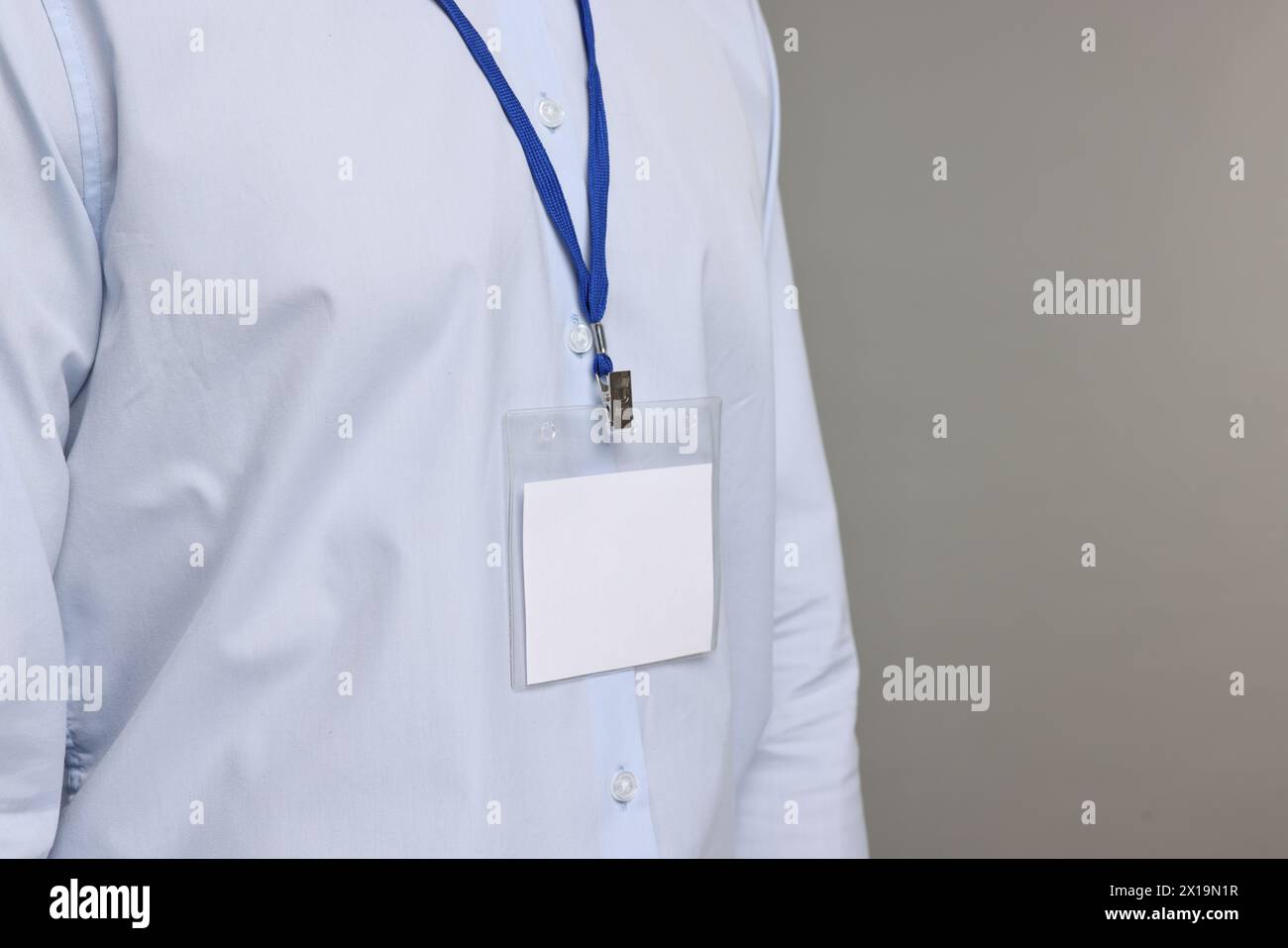 Uomo con distintivo vuoto su sfondo grigio, primo piano. Spazio per il testo Foto Stock