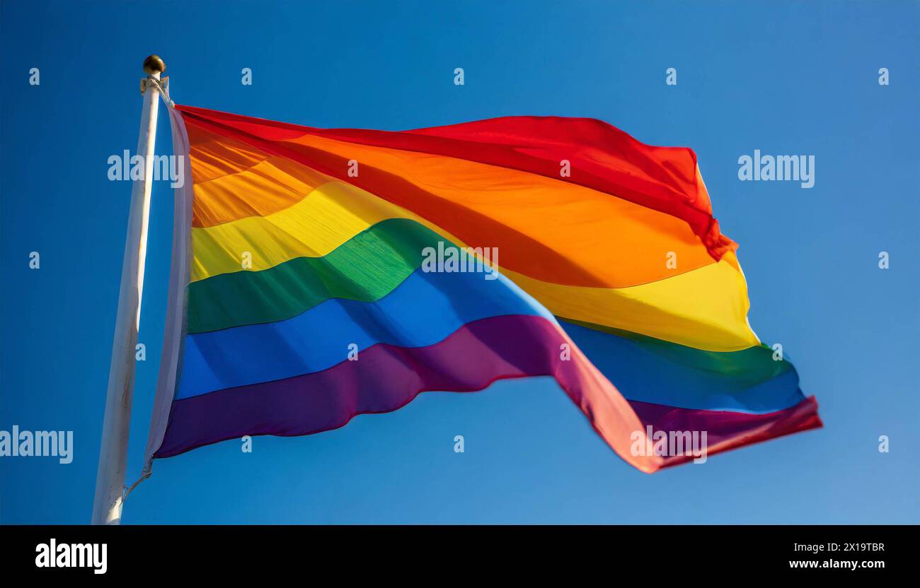 Die Regenbogenfahne flattert im Wind, isoliert, gegen den blauen Himmel, mit einer solchen Fahne wird in zahlreichen Kulturen weltweit Die Stimmung fü Foto Stock