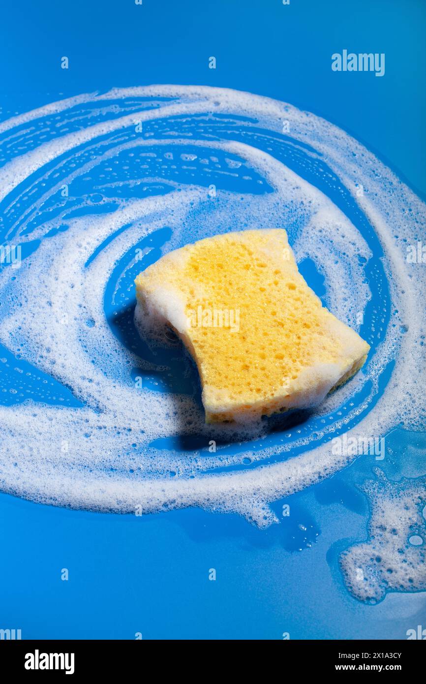 spugna per pulizia detergente schiuma sapone su sfondo blu, concetto di lavaggio domestico Foto Stock