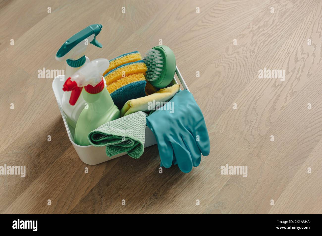 Spazzole, flaconi con liquidi detergenti, spugne e guanti in gomma. Prodotti per la pulizia su pavimenti in legno. Foto Stock