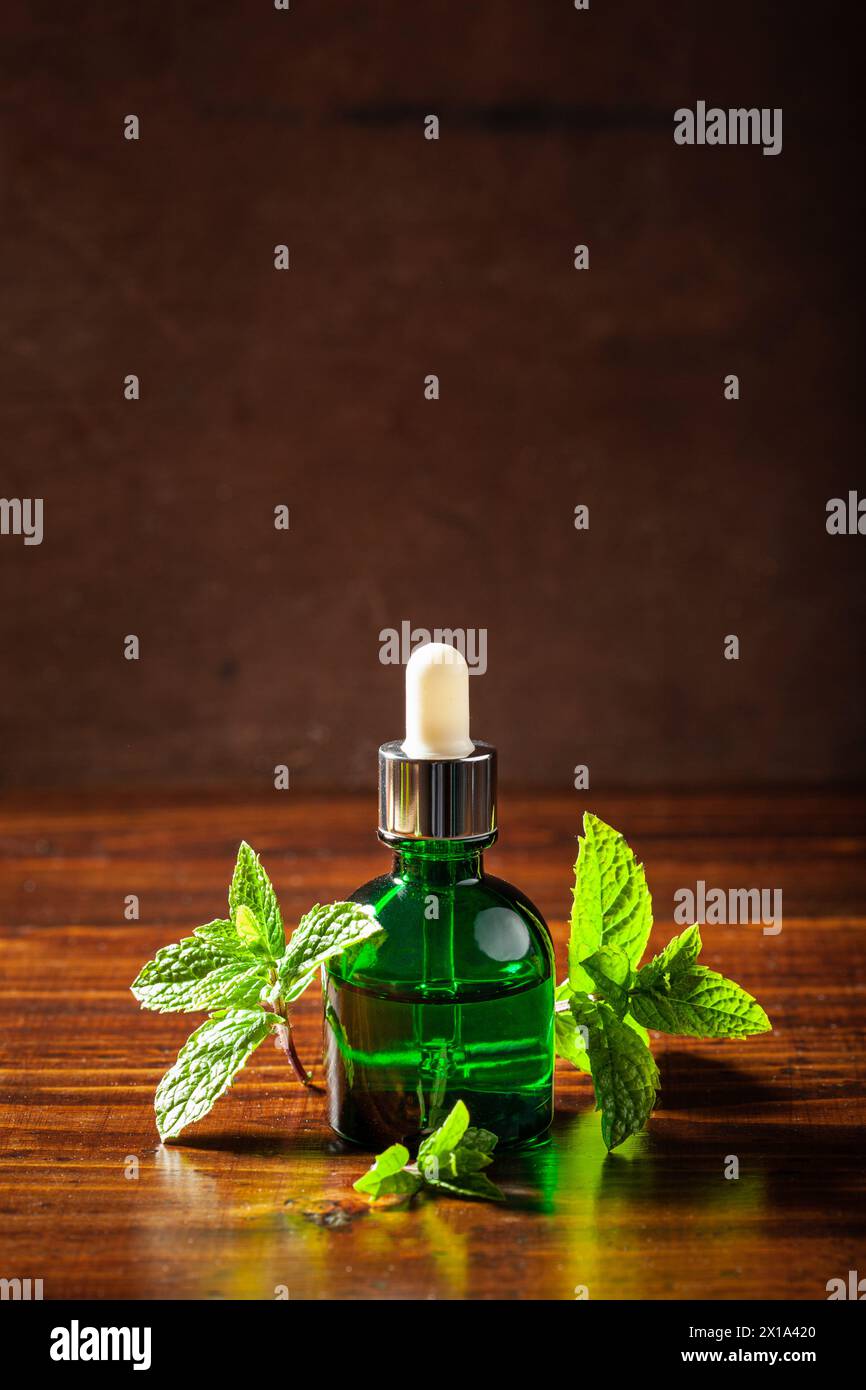Foglie di menta fresca, olio essenziale su tavola di legno Foto Stock