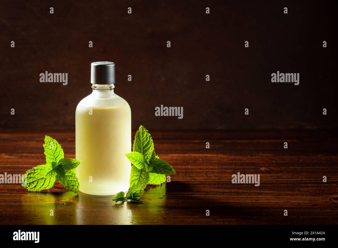 Foglie di menta fresca, olio essenziale su tavola di legno Foto Stock
