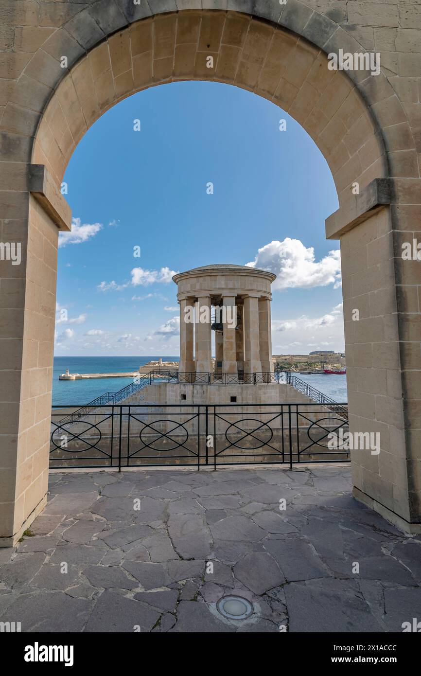 Il Monumento alla Guerra della Campana d'assedio incorniciato da un arco dei Giardini Barrakka inferiori, la Valletta, Malta Foto Stock