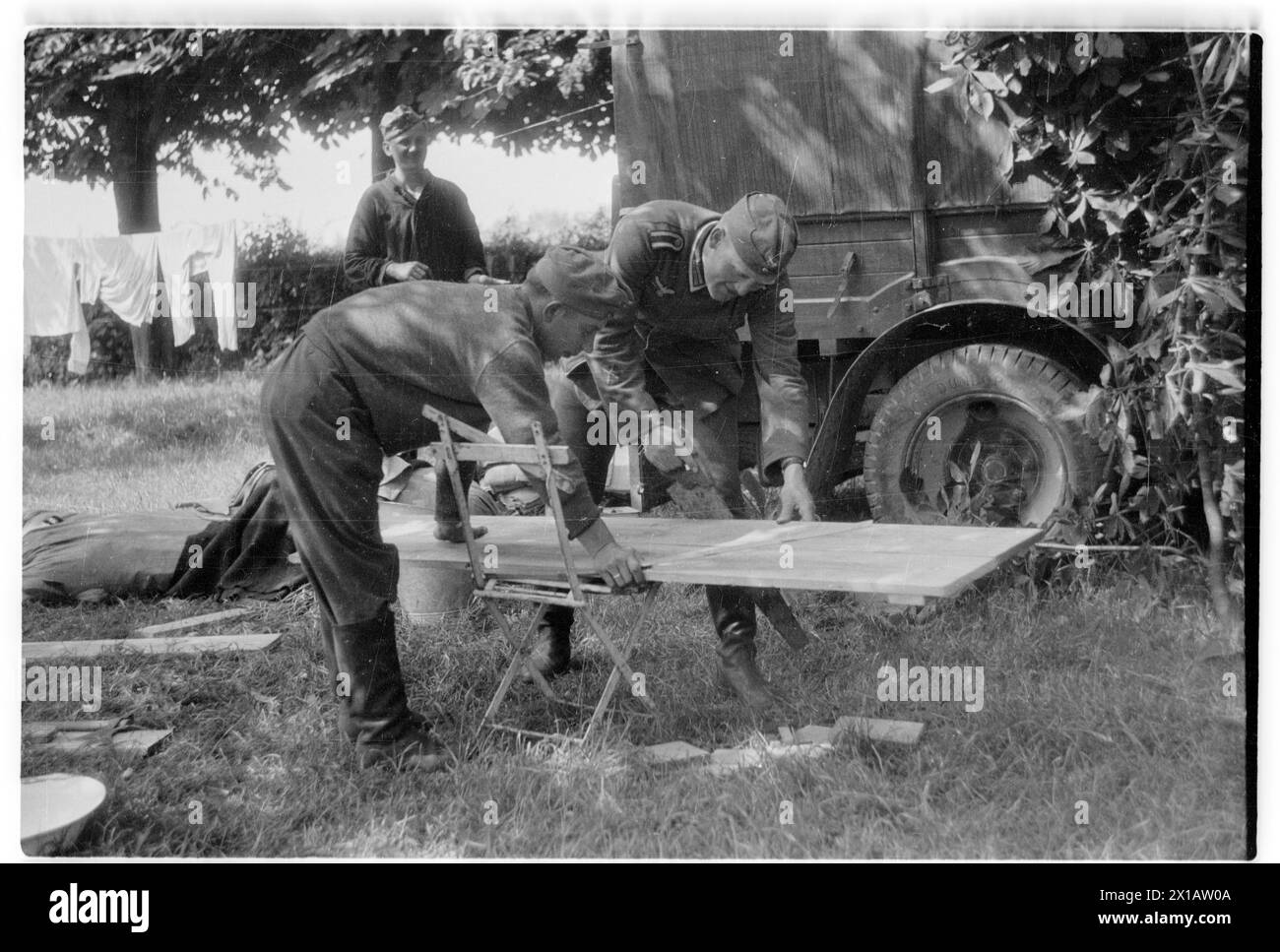 Lavori nel bivacco durante la campagna francese, due soldati macchinano un asse nella schiena osservano il fotografo Joe J. Heydecker sorridendo della scena, 1940 - 19400101 PD3951 - Rechteinfo: Diritti gestiti (RM) Foto Stock
