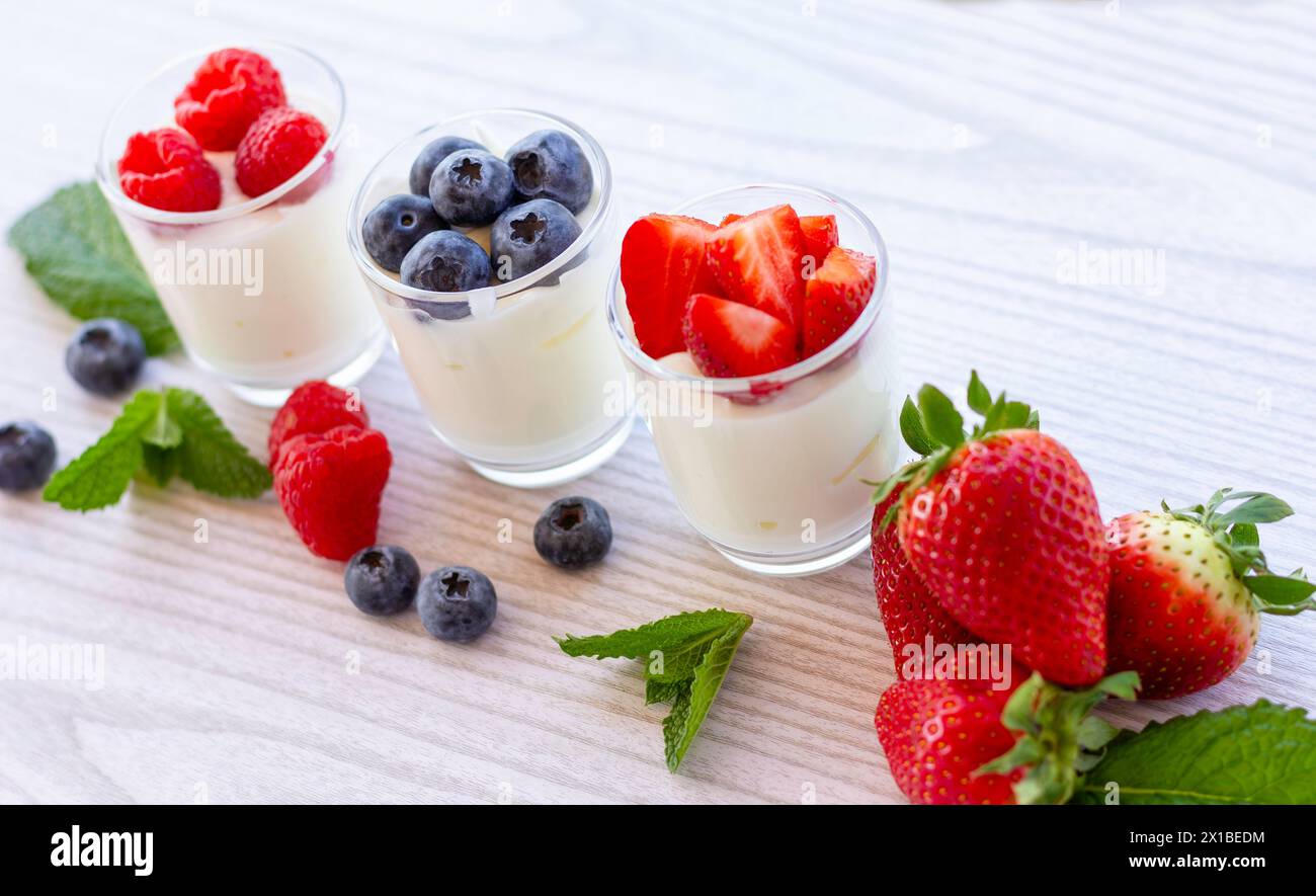 3 mini pentole di yogurt alla frutta con bacche miste e menta Foto Stock