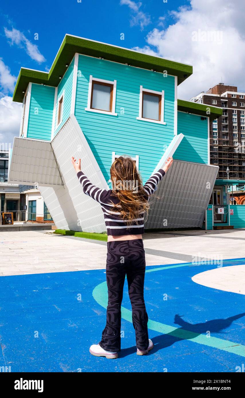 Giovane ragazza di 7 anni che visita l'attrazione turistica Upside Down House sul lungomare di Brighton, Sussex, Inghilterra, Regno Unito Foto Stock