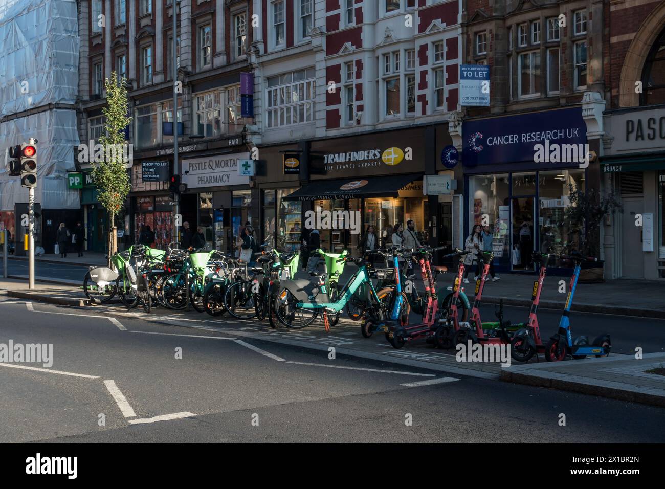 Biciclette elettriche e scooter ti attendono a tariffe nella Kensington High Street di Londra. Foto Stock